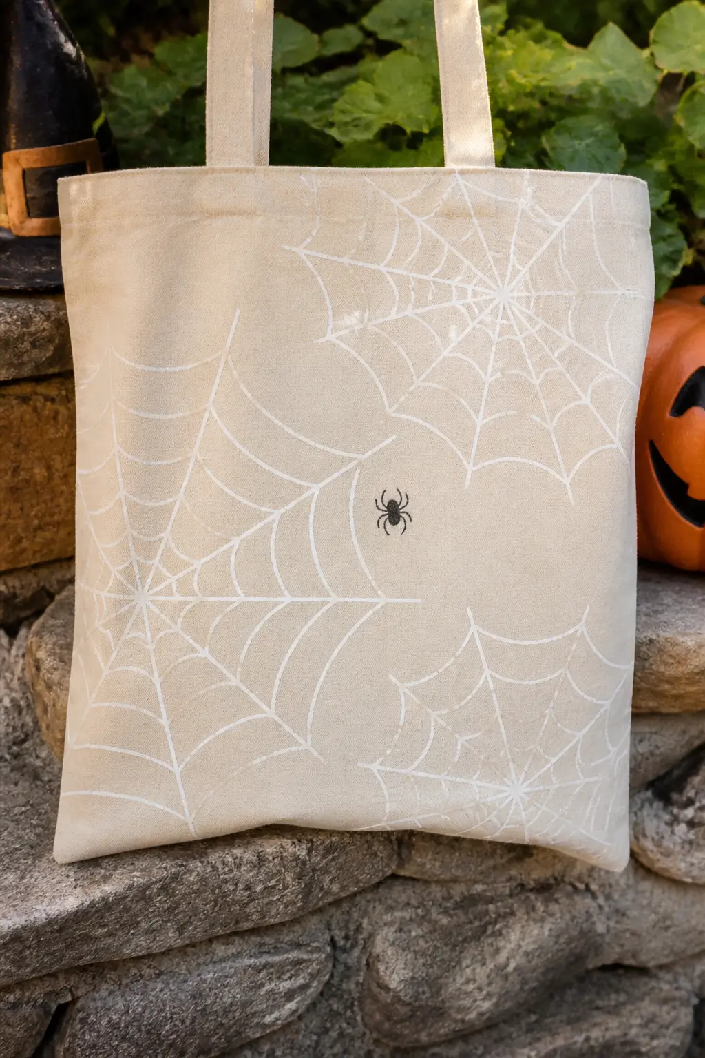 Spider Web Stencil Scattered Across the Bag — Cut a spider web from acetate or thick card stock so it holds its shape through multiple uses. Halloween tote