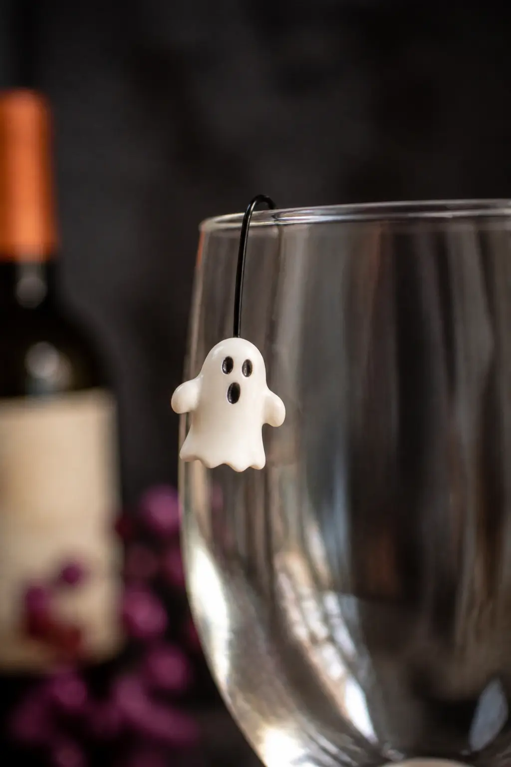Ghost Drink Stirrer Charm — White clay or white shrink plastic, cut into a ghost silhouette, threaded onto a short length of black wire that loops over the