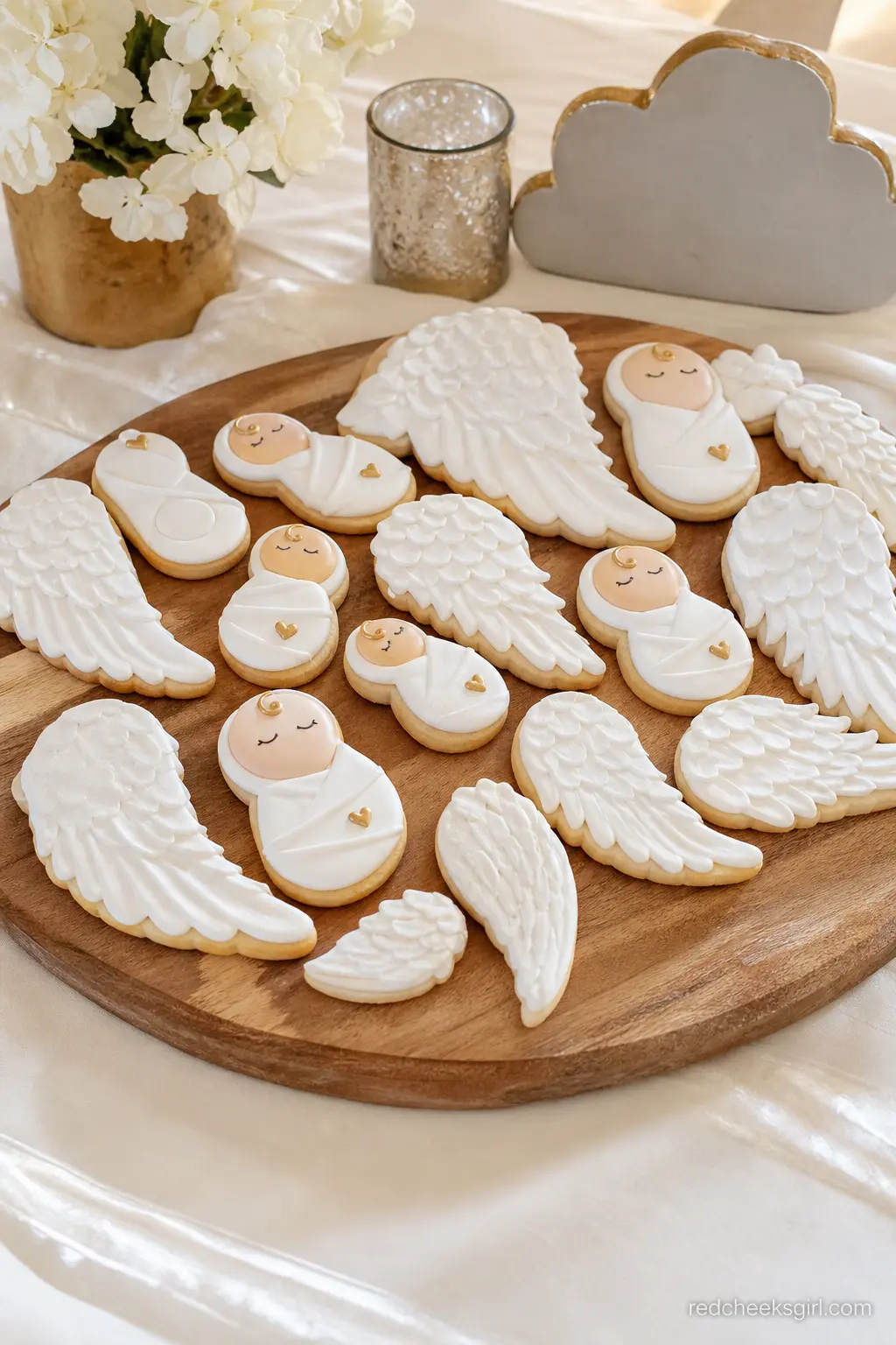 An Angel Wing and Bundle Cookie Platter — Custom sugar cookies shaped like angel wings and swaddled bundles, iced in white and cream with the smallest gold