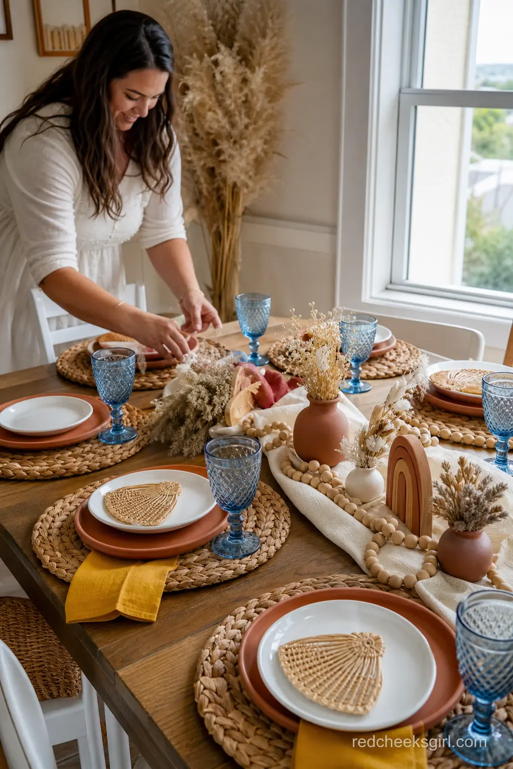 Terracotta and Rattan Place Settings — Terracotta chargers under white plates, woven rattan placemats and short blue goblets give the table a warm, earthy