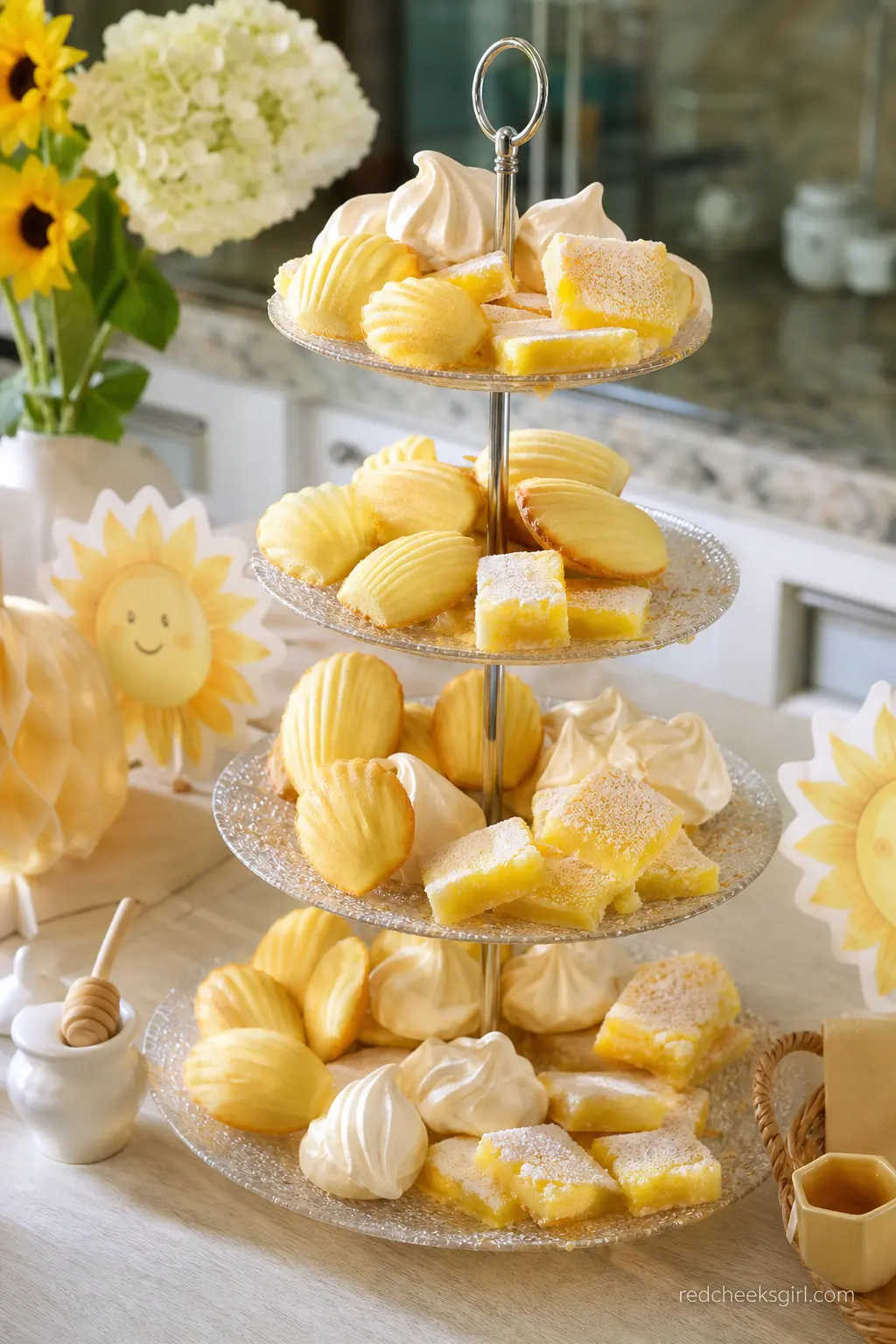 Honey and Lemon Dessert Tower — A tall dessert tower stacked with lemon bars, honey madeleines and small meringues in pale yellow and cream skips the sun motif