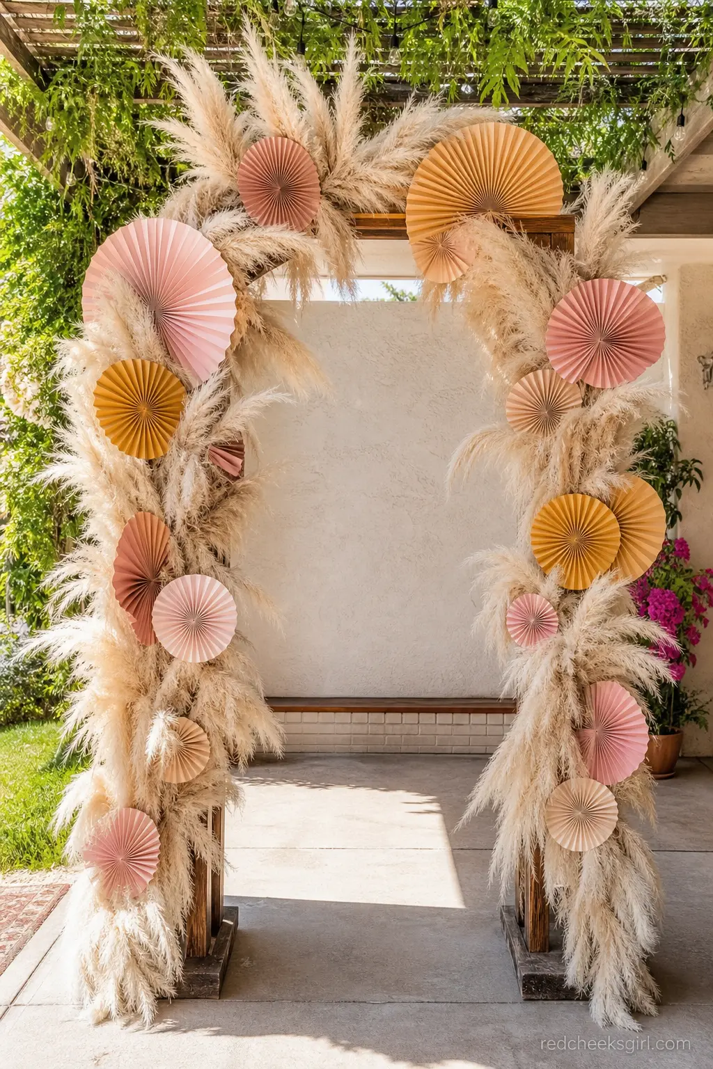 Pampas and Paper Sun Ray Arbor — A freestanding arbor wrapped in dried pampas grass and oversized paper sun rays makes an entrance without a single fresh