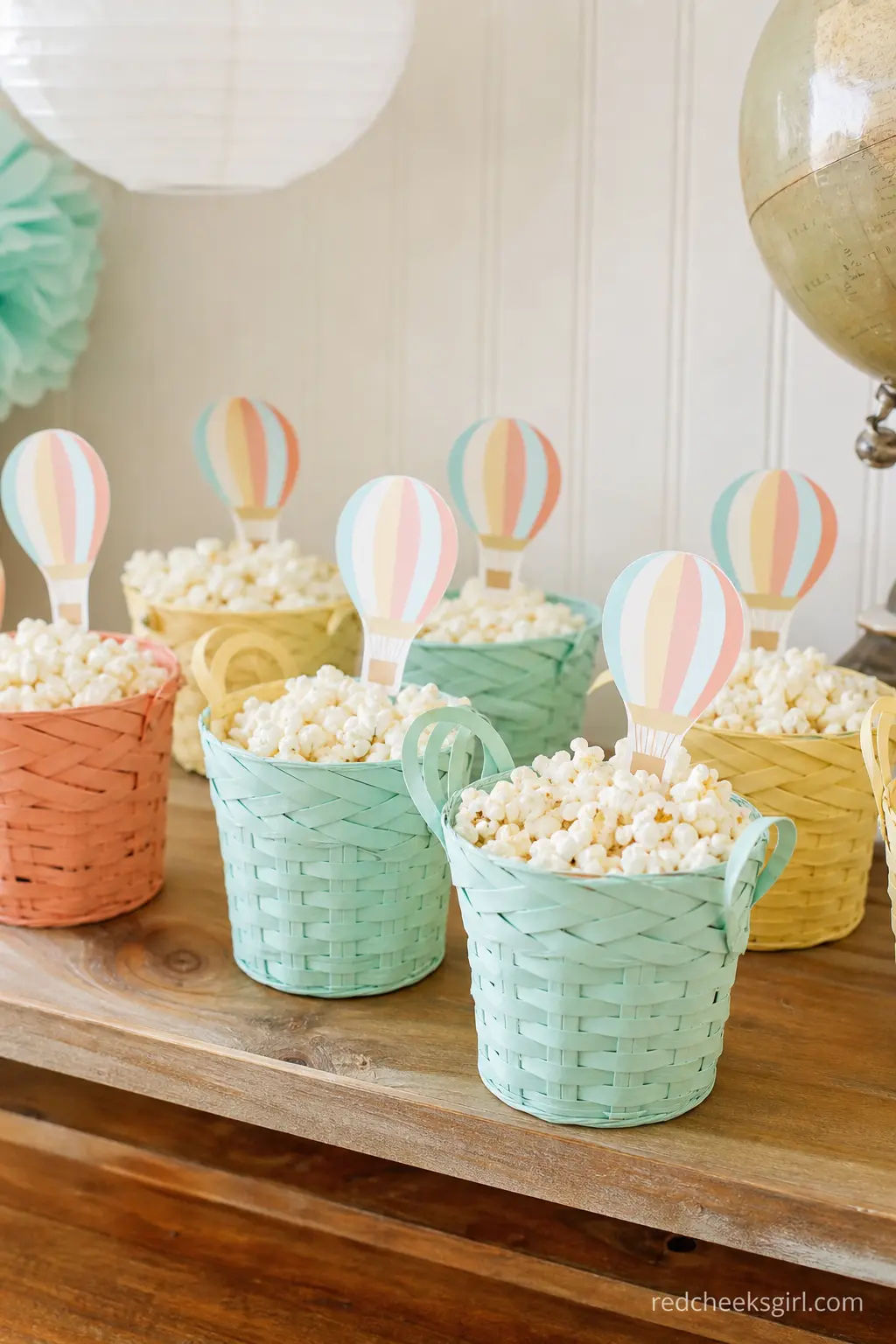 Rainbow Pastel Popcorn Basket Favors — Small woven baskets in coral, mint and buttery yellow, each filled with popcorn and topped with a paper balloon pick