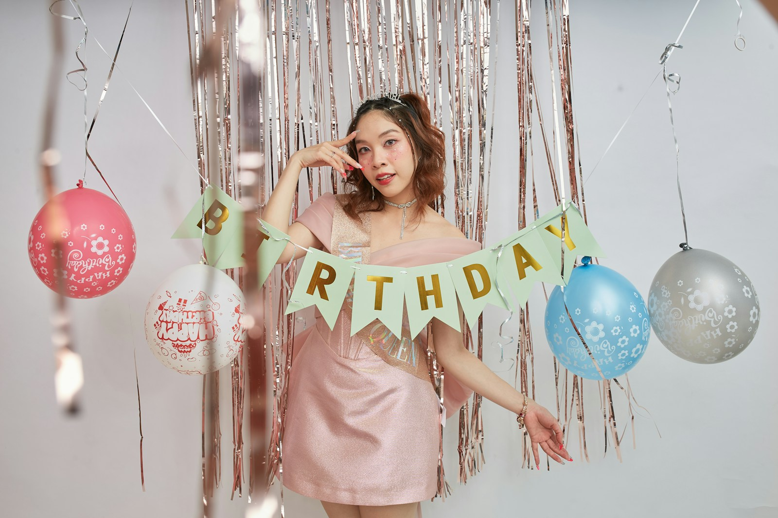 A woman in a pink dress holding a happy birthday banner