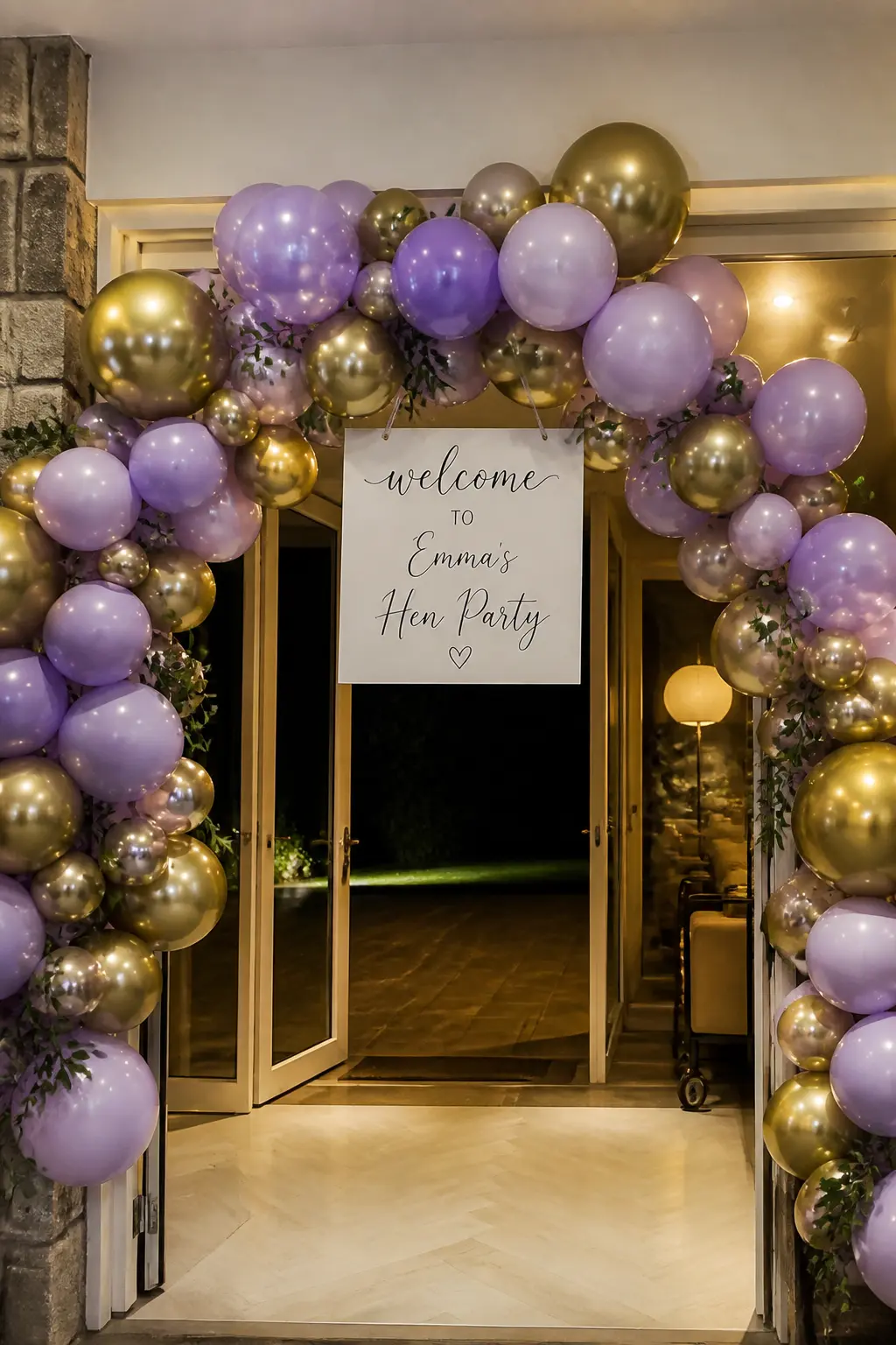 Lavender and Gold Arch Over a Hen Party Entrance with a Hand-Lettered Sign — Gold with lavender leans evening rather than daytime, which suits a hen party that