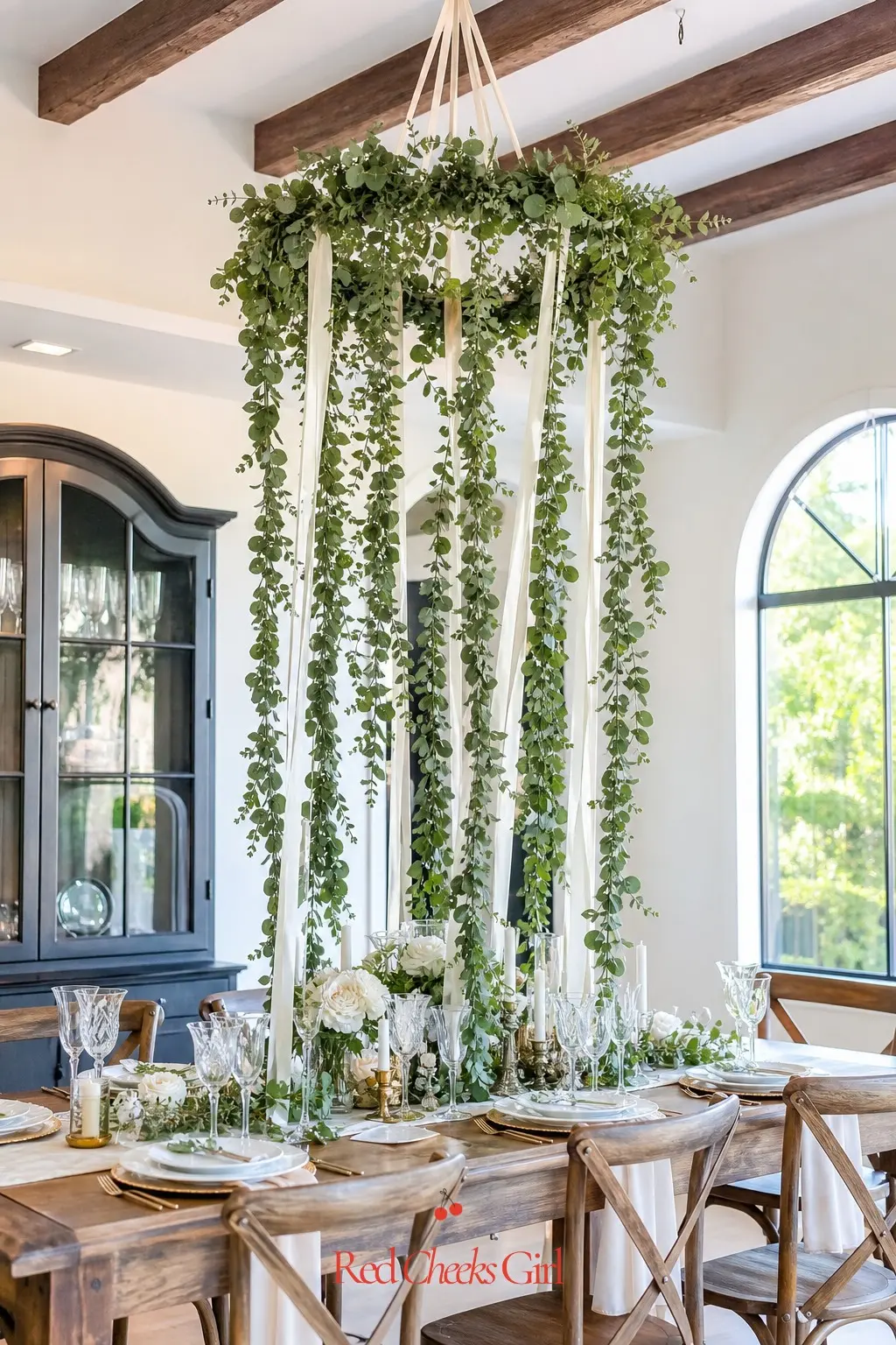 Hanging Greenery Chandelier — Trailing eucalyptus and ivory ribbon hung from a ceiling beam above the table frees up every inch of tablecloth for food and