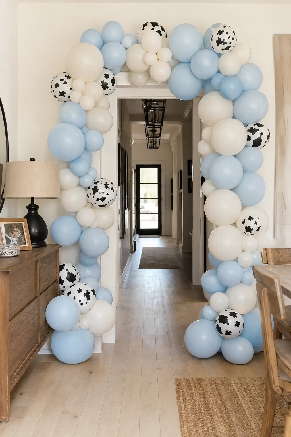 Cloud Blue and Cow Print Arch — A loose organic garland over the doorway sets the whole tone before guests are even inside. My first rodeo birthday boy