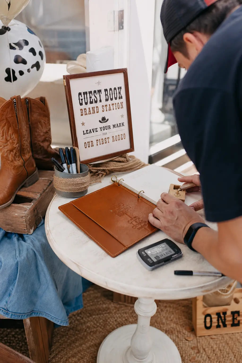 Guest Book Brand Station — Instead of a notebook, guests press a thumbprint onto a cream cardstock sheet and a marker turns it into a tiny cow with a name