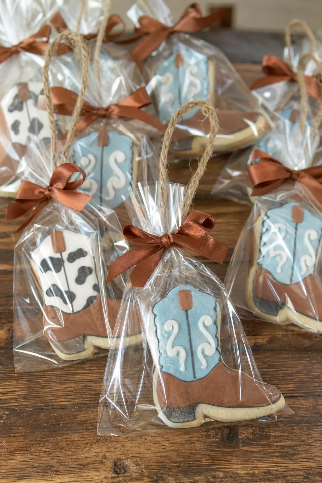 Rope-Handled Boot Cookie Bags — A single iced boot cookie, sealed in a clear cellophane bag with a cognac ribbon and a jute rope loop handle, turns dessert