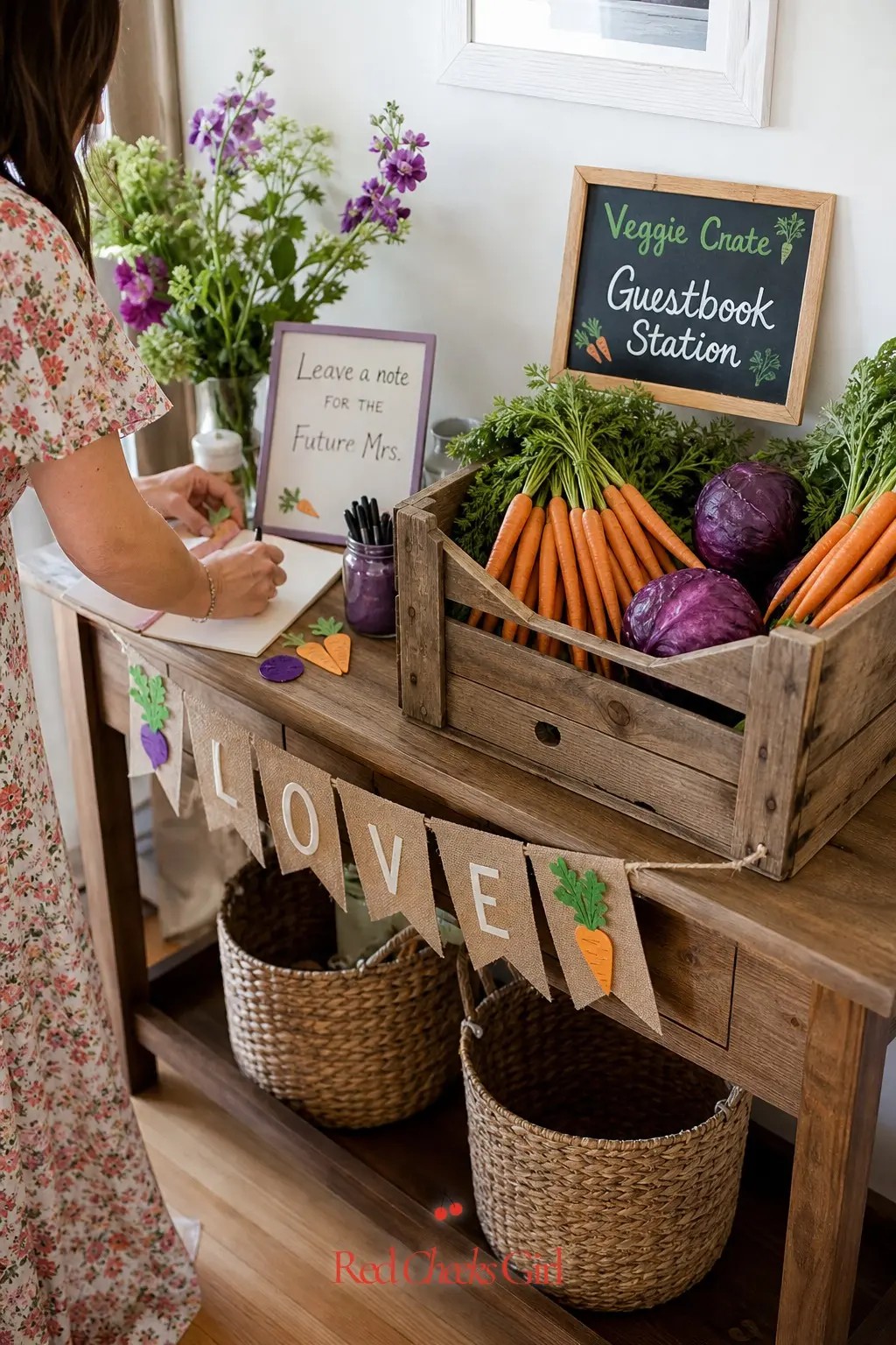 Veggie Crate Guestbook Station — A small crate filled with orange carrots and a purple cabbage sits next to the guestbook, so signing in feels like part of the
