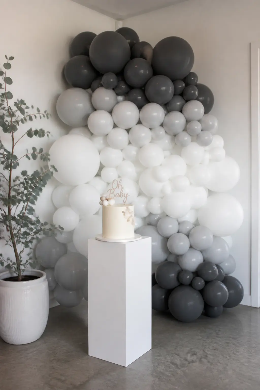 Grey to White Garland Behind a Modern Baby Shower Cake — This garland is the quietest entry in the article. Ombre balloon arch