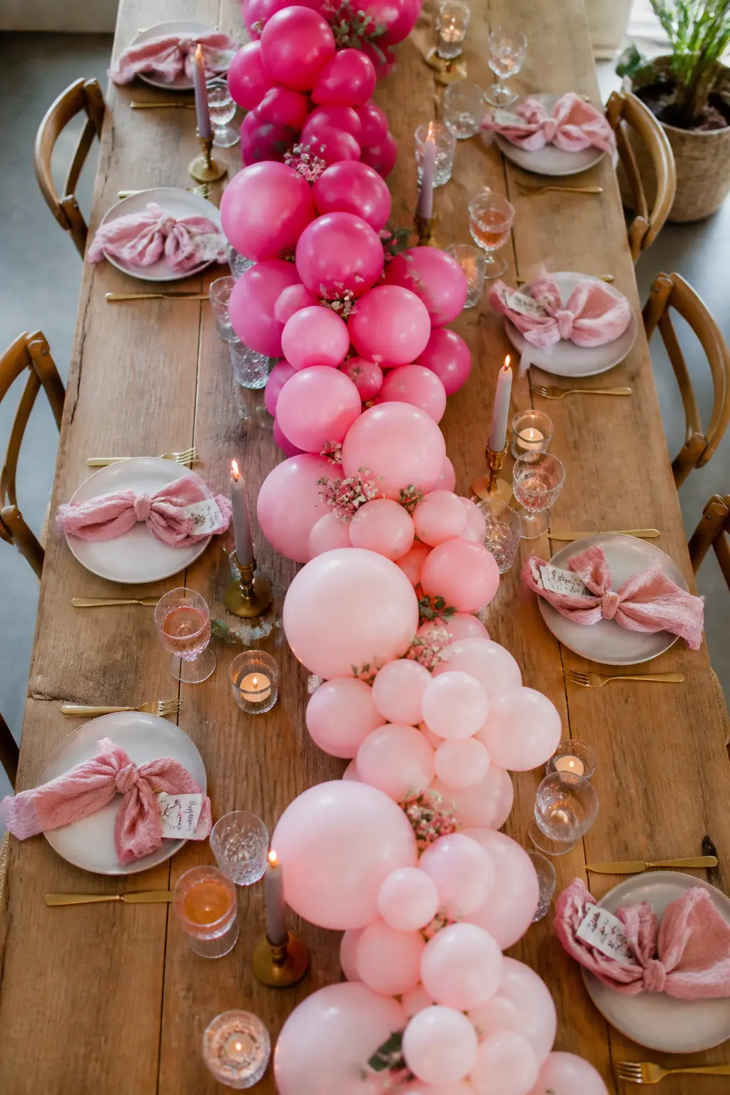 Hot Pink to Blush Low Garland Down a Hen Party Table — This garland runs along the centre of a long table at low height, not up a wall. Ombre balloon arch