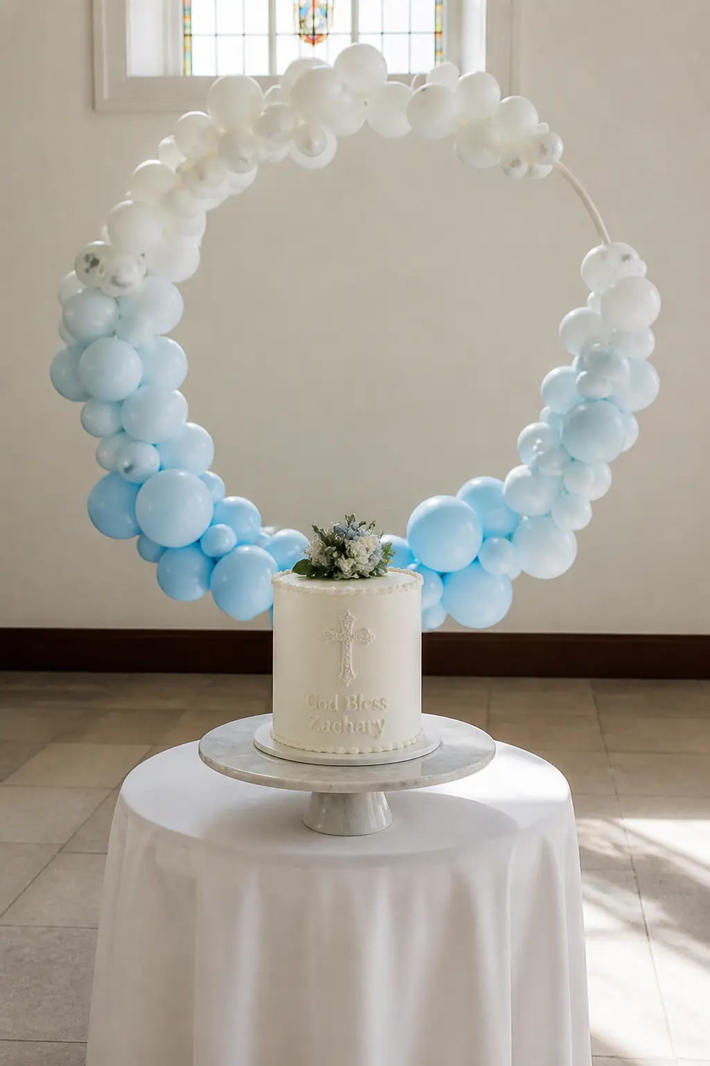 Pale Blue to White Circle Above a Christening Cake — A balloon circle, sometimes called a hoop arch, sits above the cake table on a single stand and takes up
