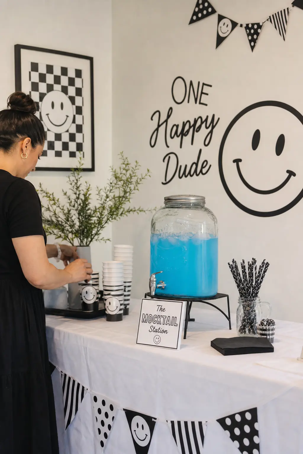 The Mocktail Station — A signature drink for the adults, a sky blue mocktail in a glass dispenser with black paper straws on a white linen covered table, gives