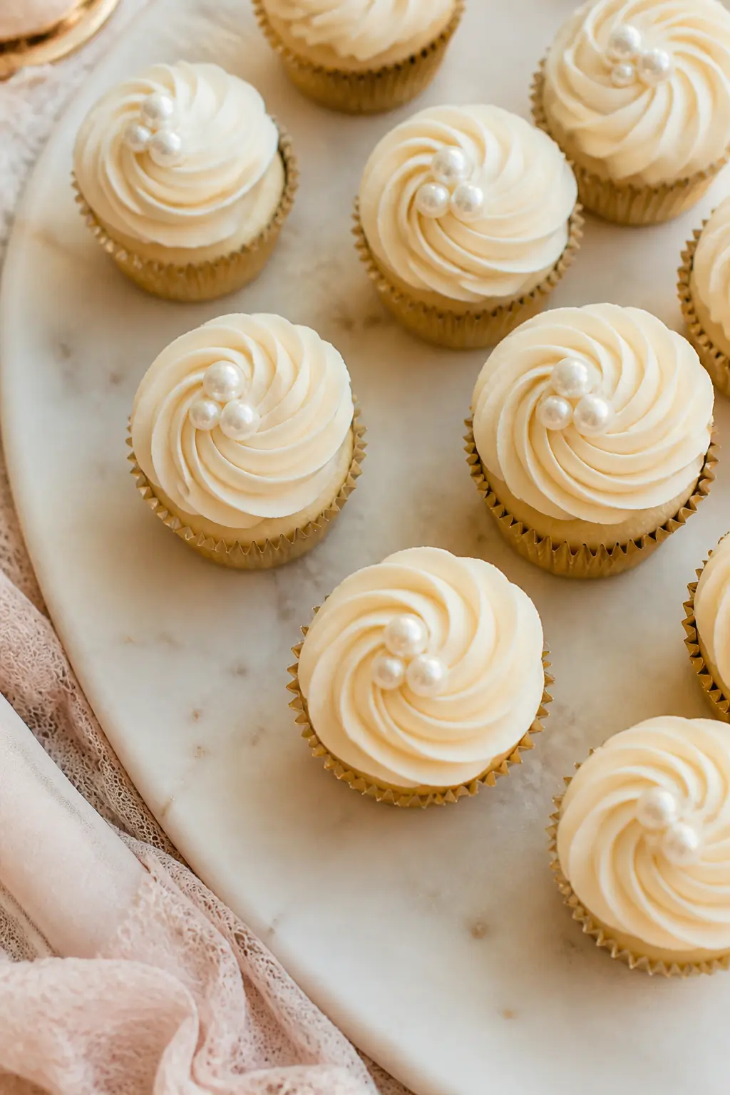 Cupcake Pearl Topper — Individual cupcakes with ivory buttercream frosting, each finished with three sugar pearls placed in a small triangle at the centre of