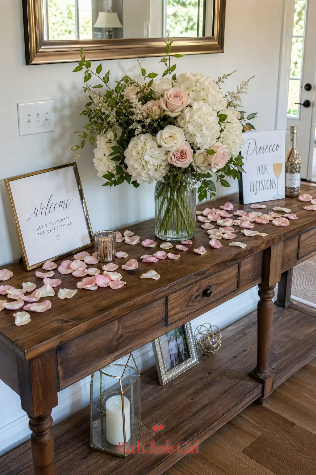 Petal-Strewn Welcome Table — A console table just inside the door, scattered with loose petals and a single oversized arrangement, tells every guest they are