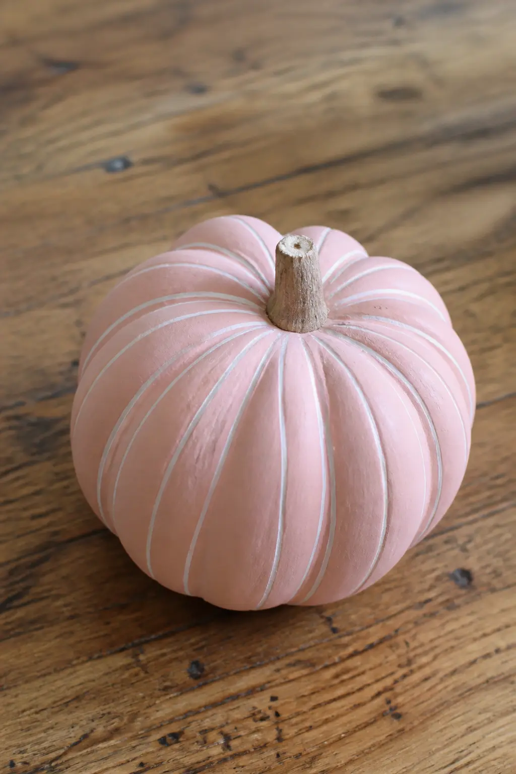 Blush With Fine White Stripes — Apply painter's tape in vertical stripes over a cured blush base, spacing the tape strips evenly around the pumpkin. Pink