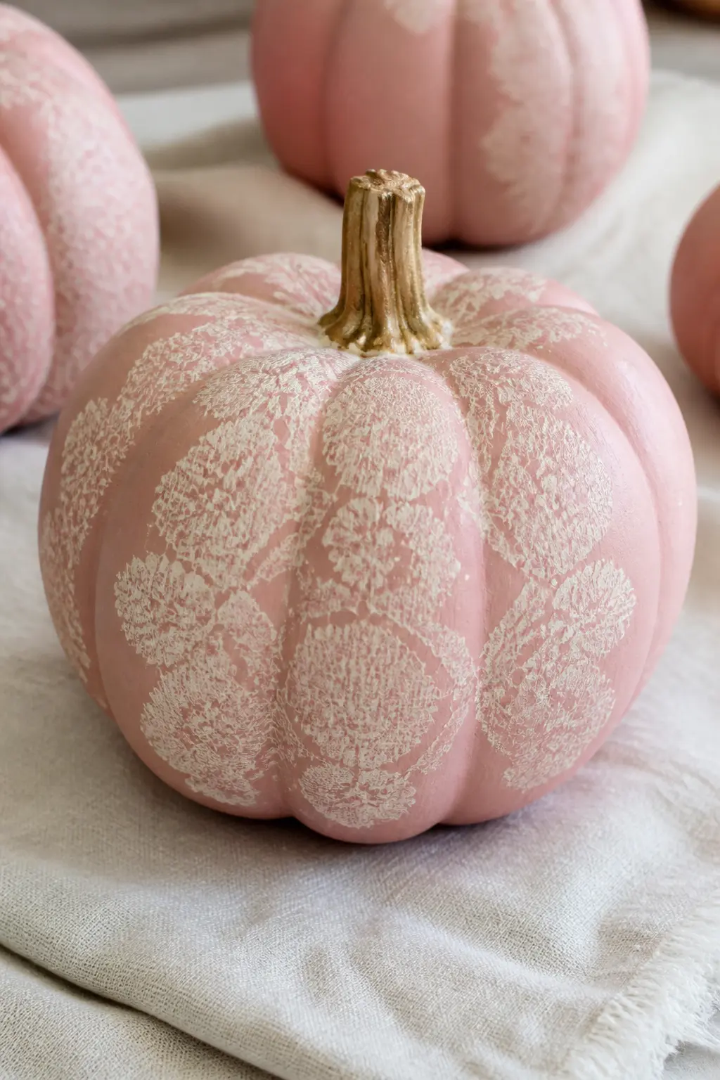 Blush With a Lace Pattern — Hold a piece of lace flat against the pumpkin surface, securing it with two pieces of tape. Pink painted pumpkin