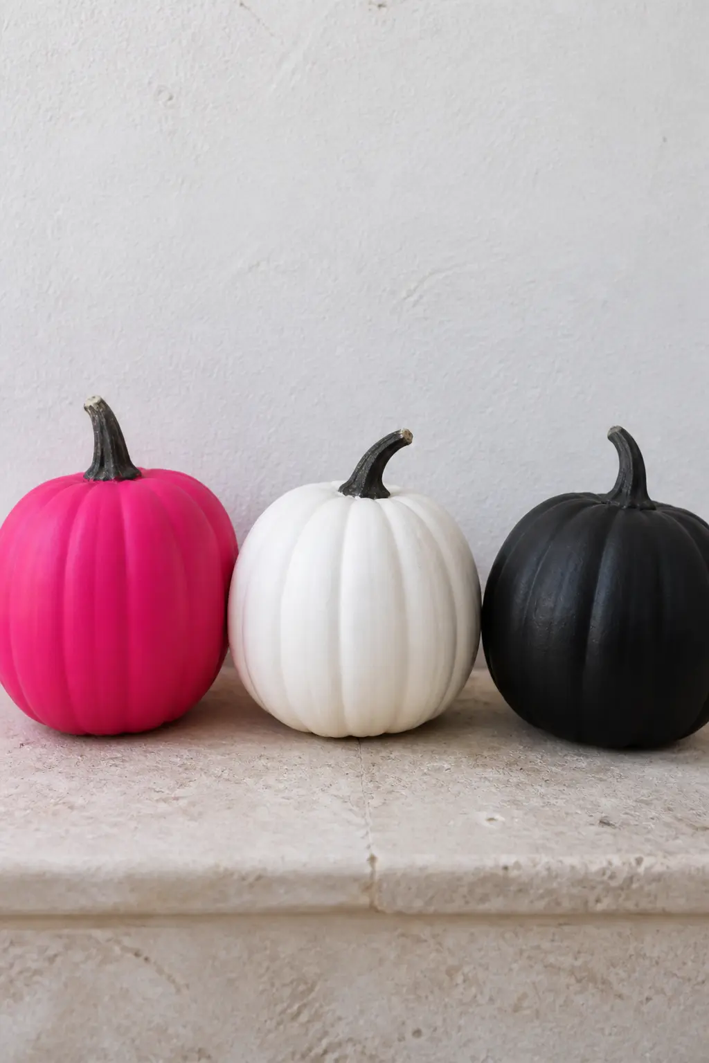 Pink With One White and One Black — Three pumpkins, all the same size: one hot pink, one white, one matte black. Pink painted pumpkin