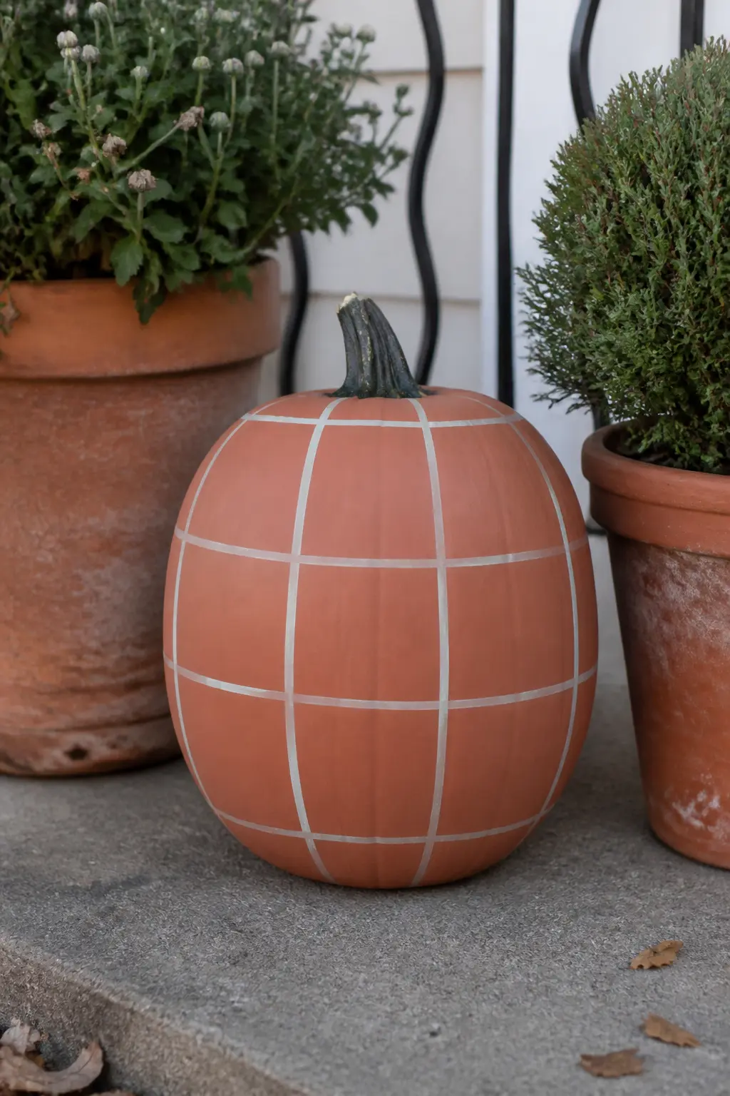 Cream Windowpane Grid on a Terracotta Pumpkin — Terracotta base paint gives this pumpkin a dusty, clay-pot quality that looks natural on a porch with real