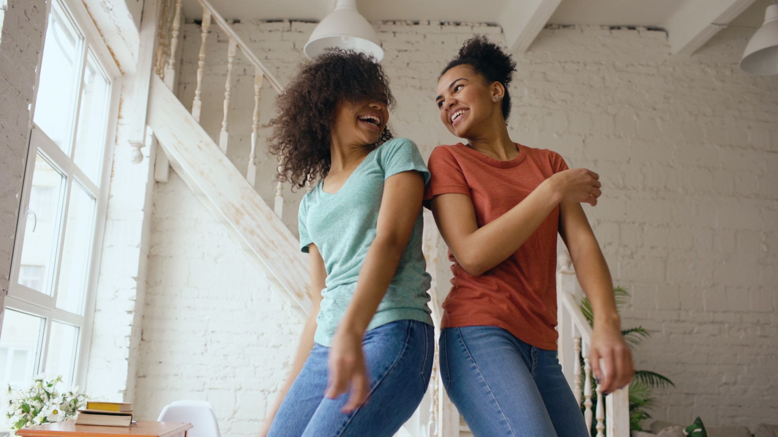 Two women dancing and laughing together indoors