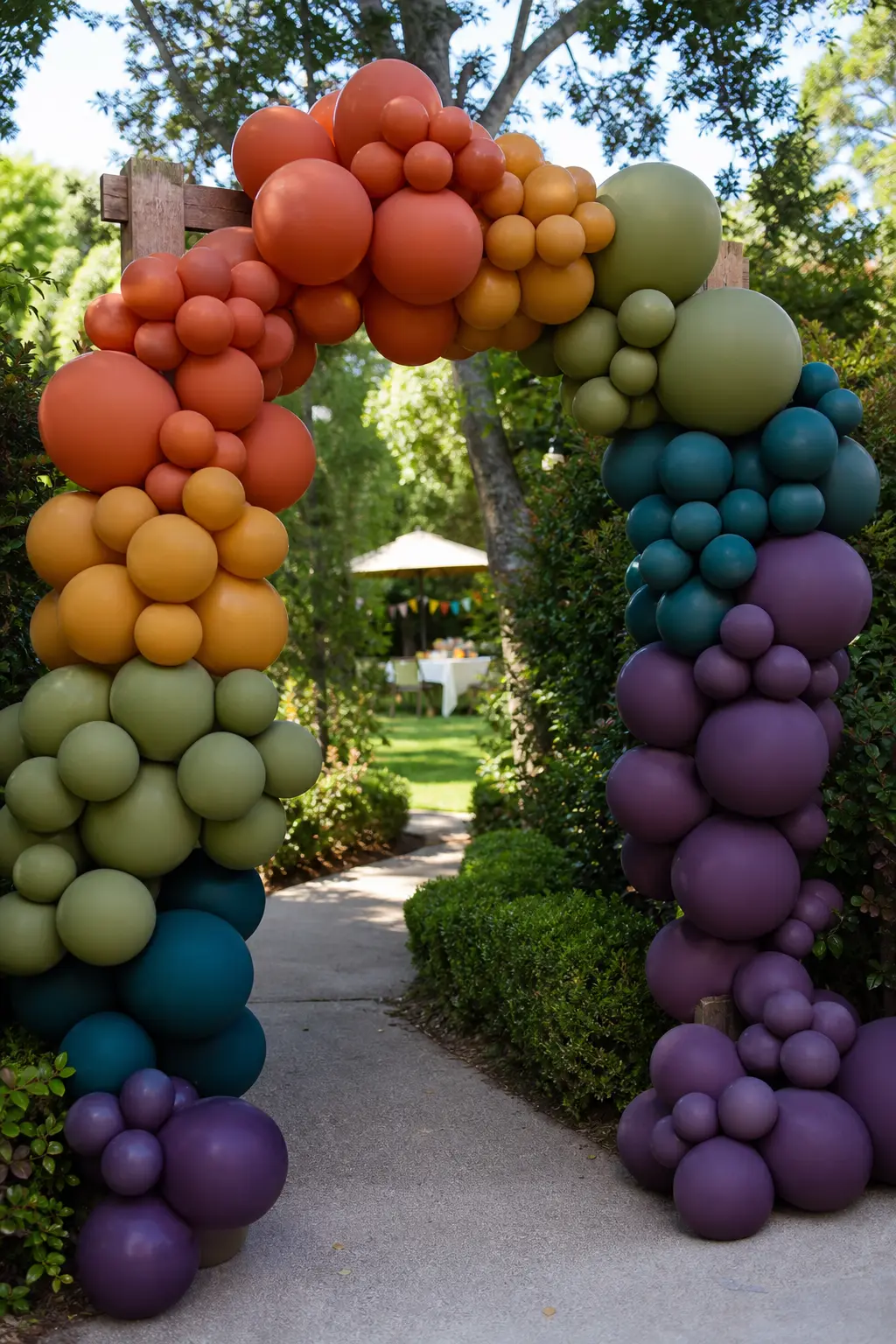 Earth-Tone Rainbow at a Garden Party Entrance — Rust, amber, olive, teal and deep plum in spectrum order, arching over a garden gate or wooden arch at the
