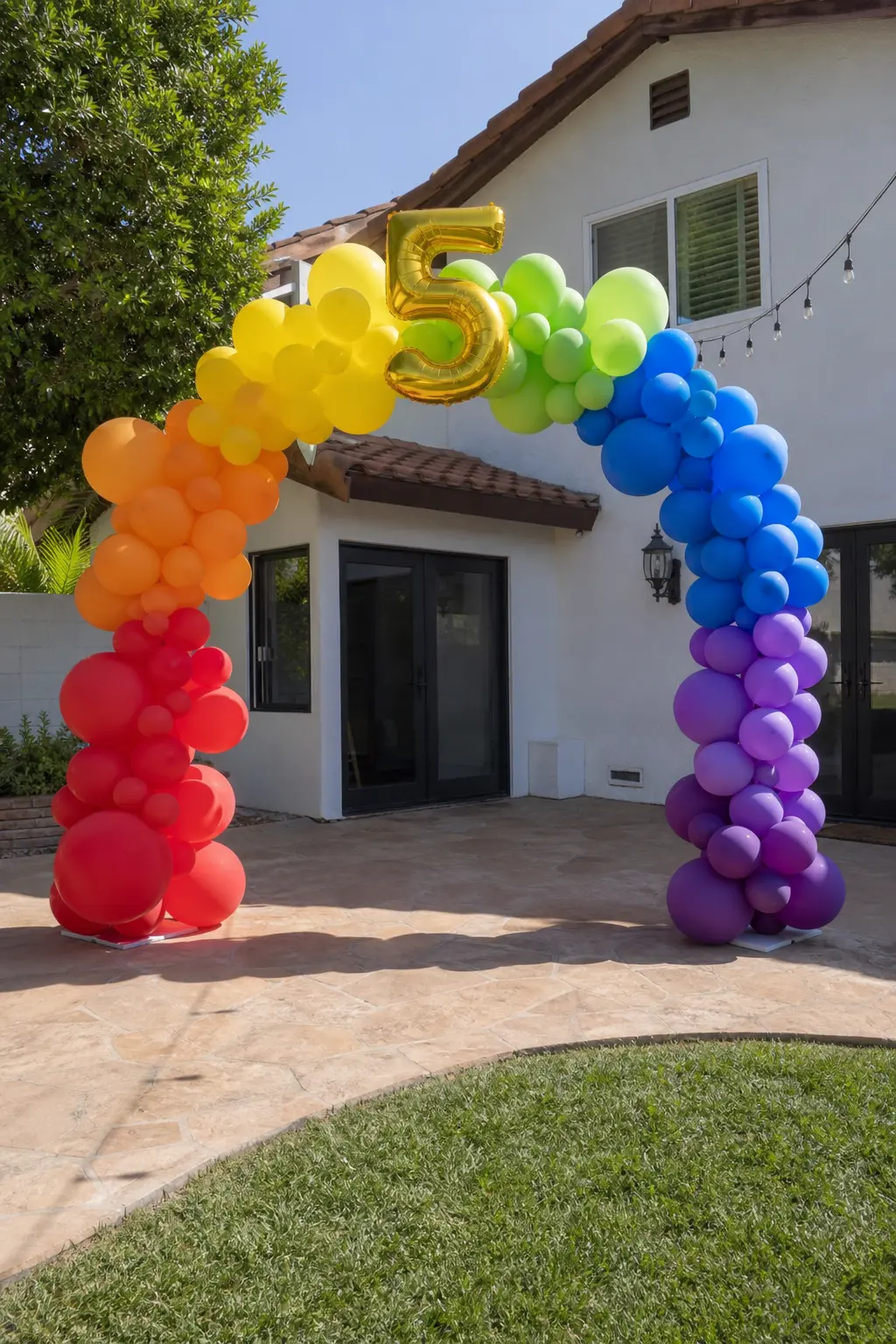 Rainbow Arch With Number Balloons at the Centre — The arch follows the full spectrum, and at the crown a foil number balloon or two digit number sits at the