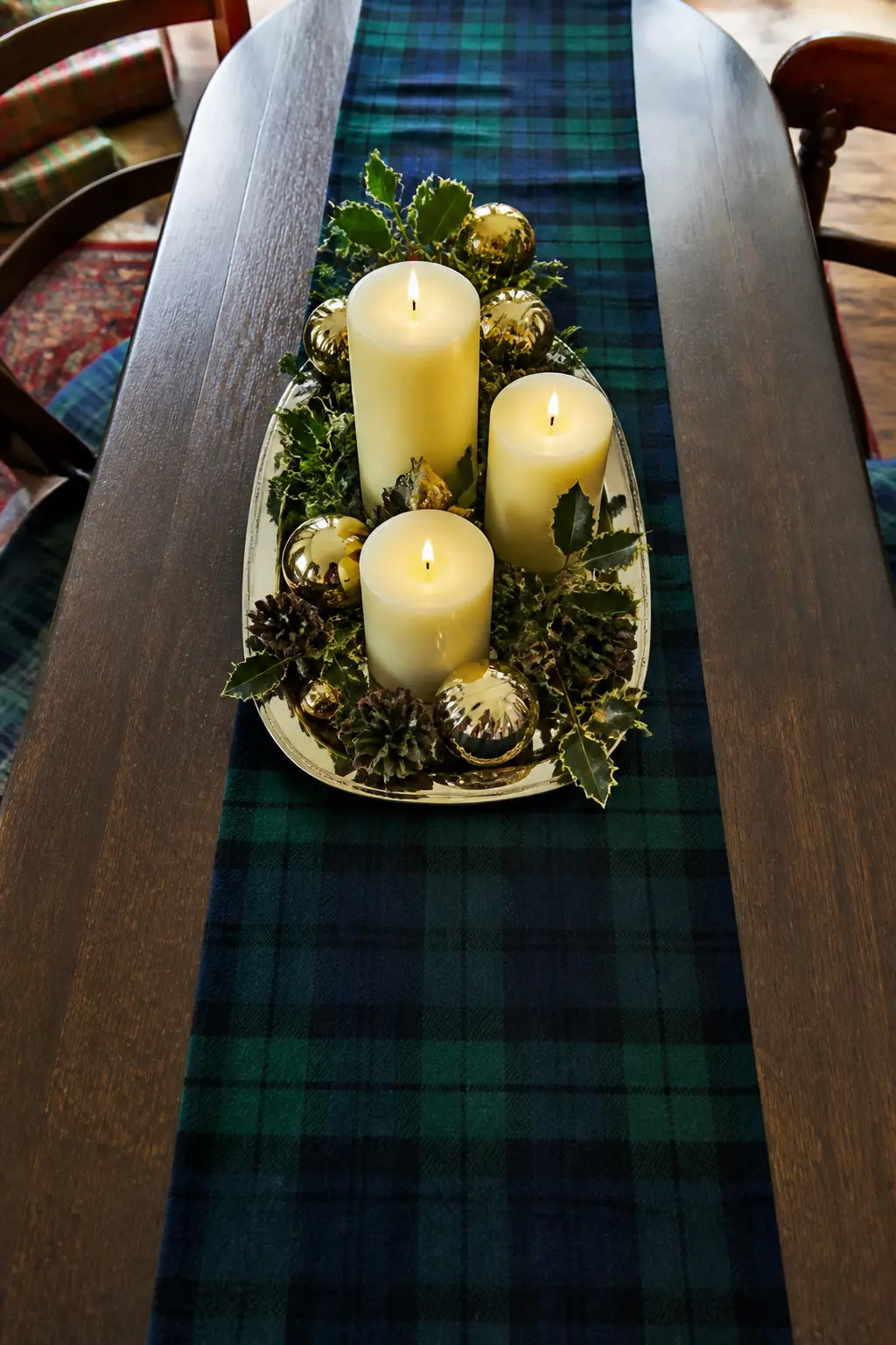 The Tartan Runner Table — Lay a navy and forest green tartan wool runner down the centre of a bare oak or dark wood table, leaving the wood visible on both