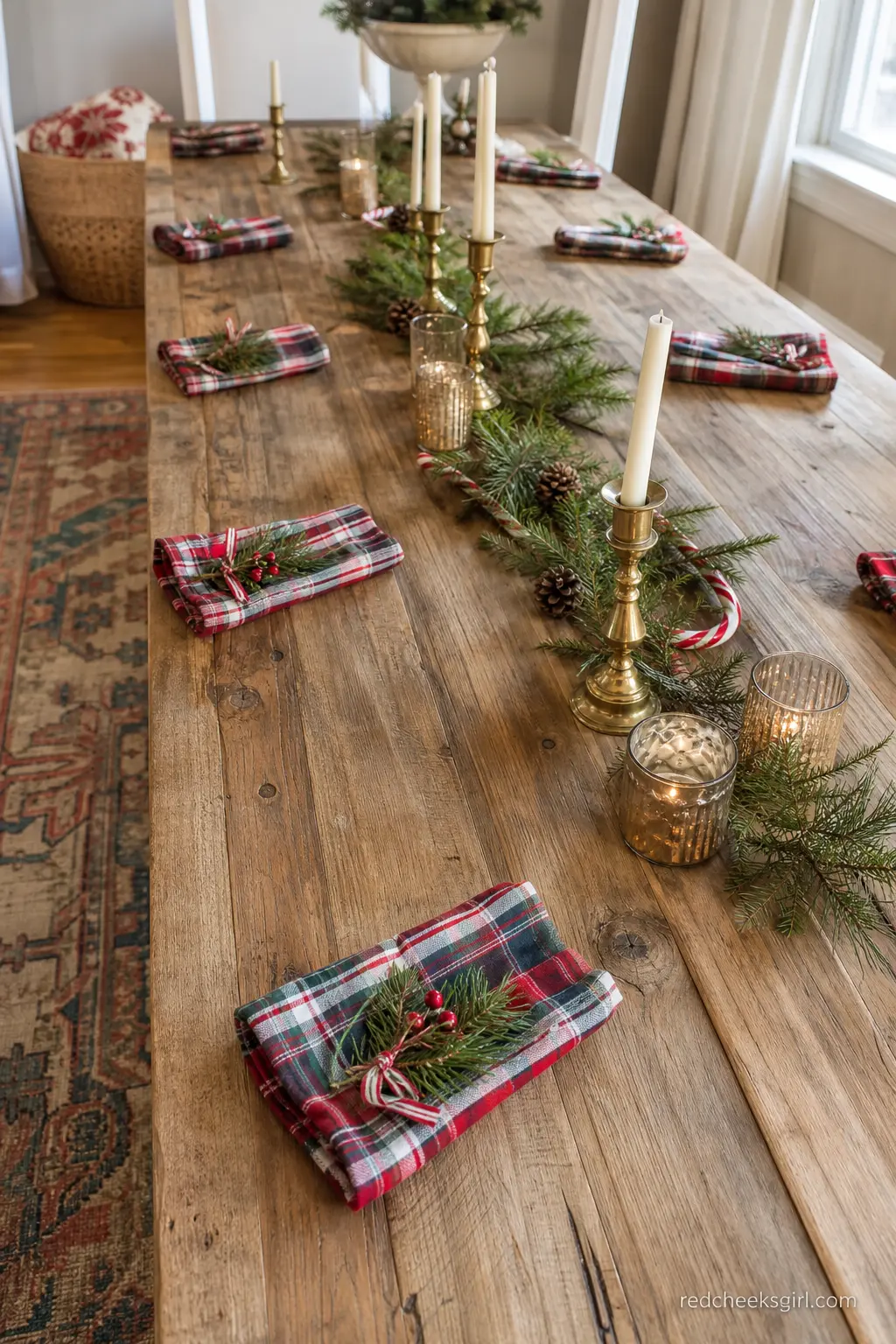 Rustic Wood Table with Plaid Napkins and Brass Candlesticks — A long rustic wood table is set with red and green plaid napkins, brass candlesticks and a small