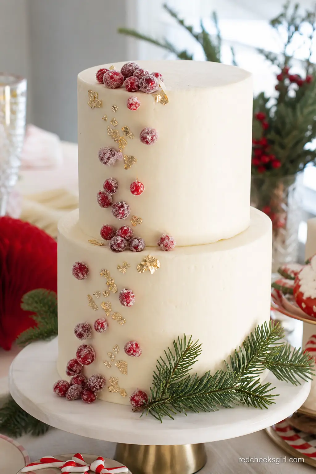 Two-Tier Ivory Buttercream Cake with Sugared Cranberries and Gold Leaf — A two tier ivory buttercream cake gets its shine from sugared cranberries and a