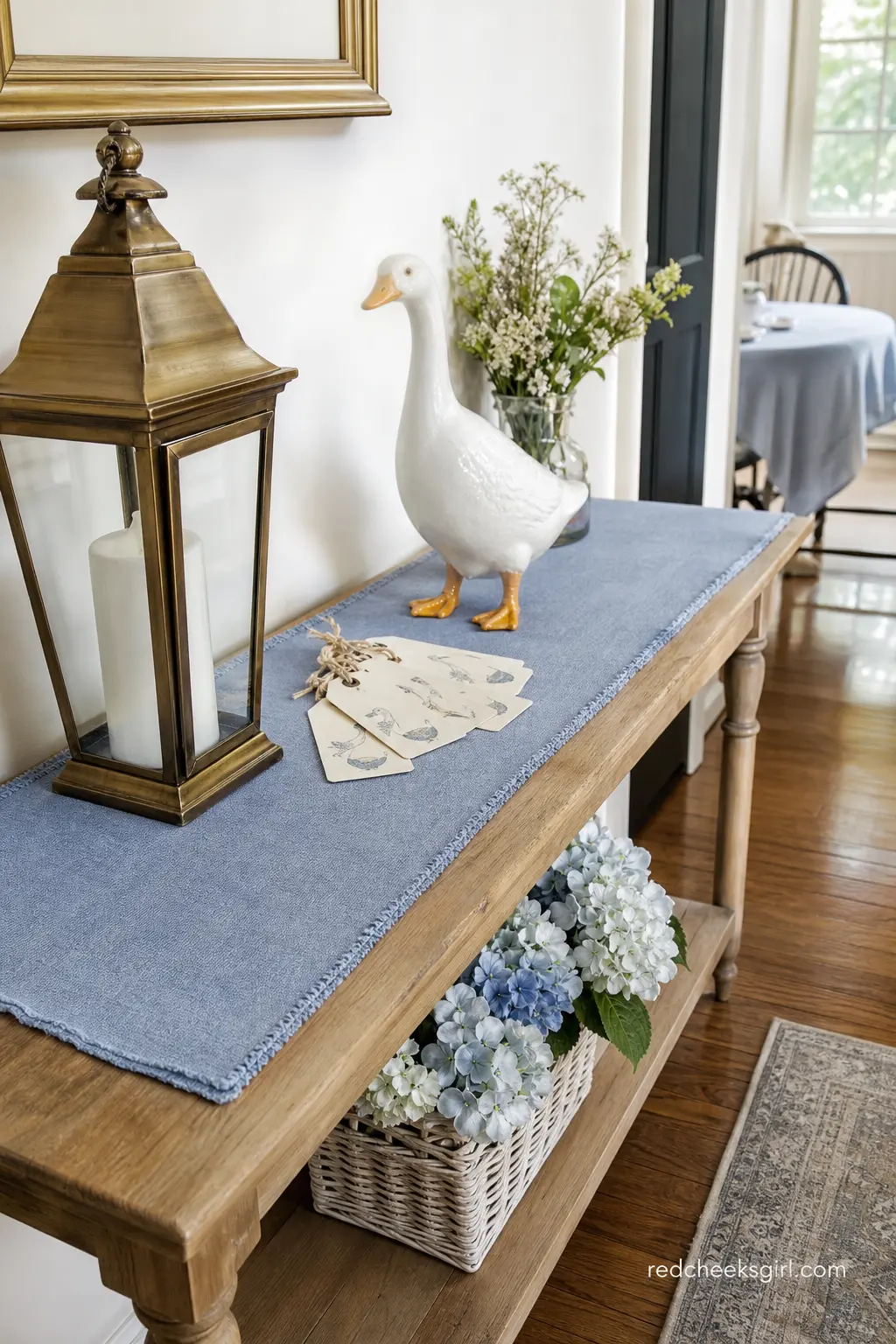 French Country Welcome Table — Instead of a backdrop, some rooms suit a small console table just inside the door: a brass lantern, a periwinkle linen runner
