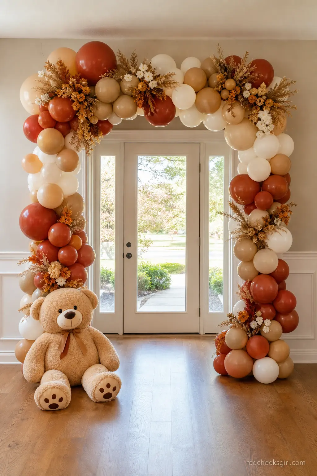 Boho Balloon Arch With A Giant Bear — Terracotta, rust and cream balloons build an arch that frames the doorway, and a single giant plush bear sitting at its