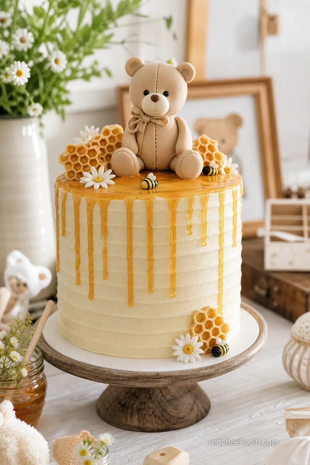 Teddy Bear Honeycomb Drip Cake — A cream buttercream cake with an amber honey drip running down the sides and a single fondant bear seated on top reads as