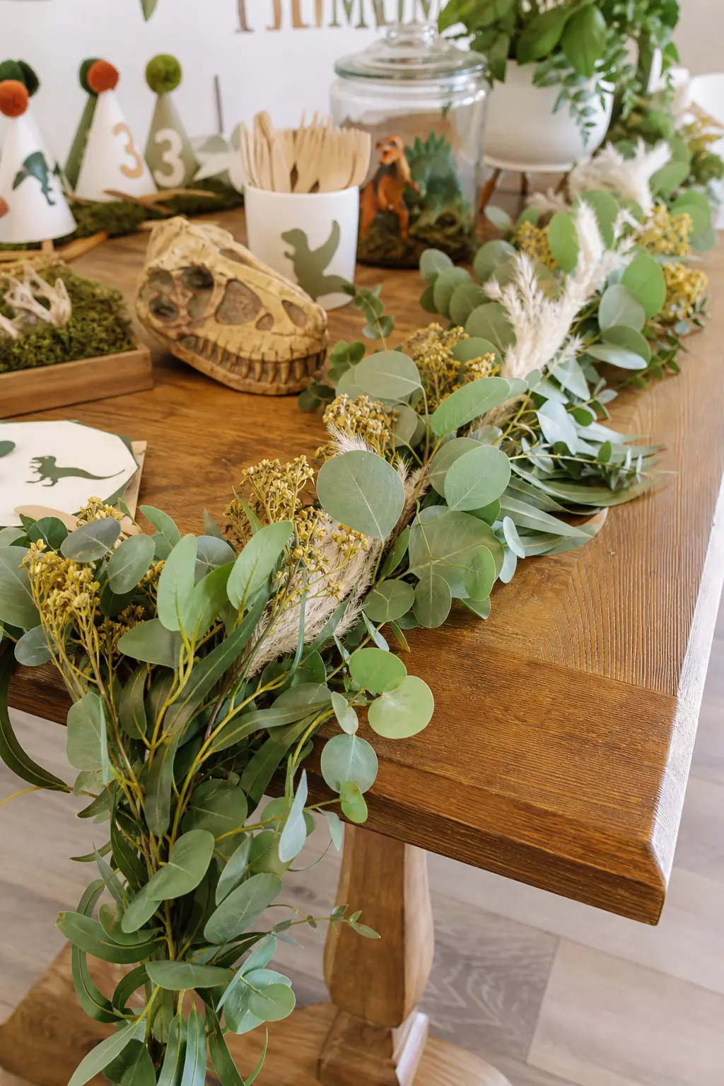 Fresh Foliage Table Garland — For a table that skips balloons entirely, a garland of eucalyptus, panicum grass and dried billy buttons draped along the table