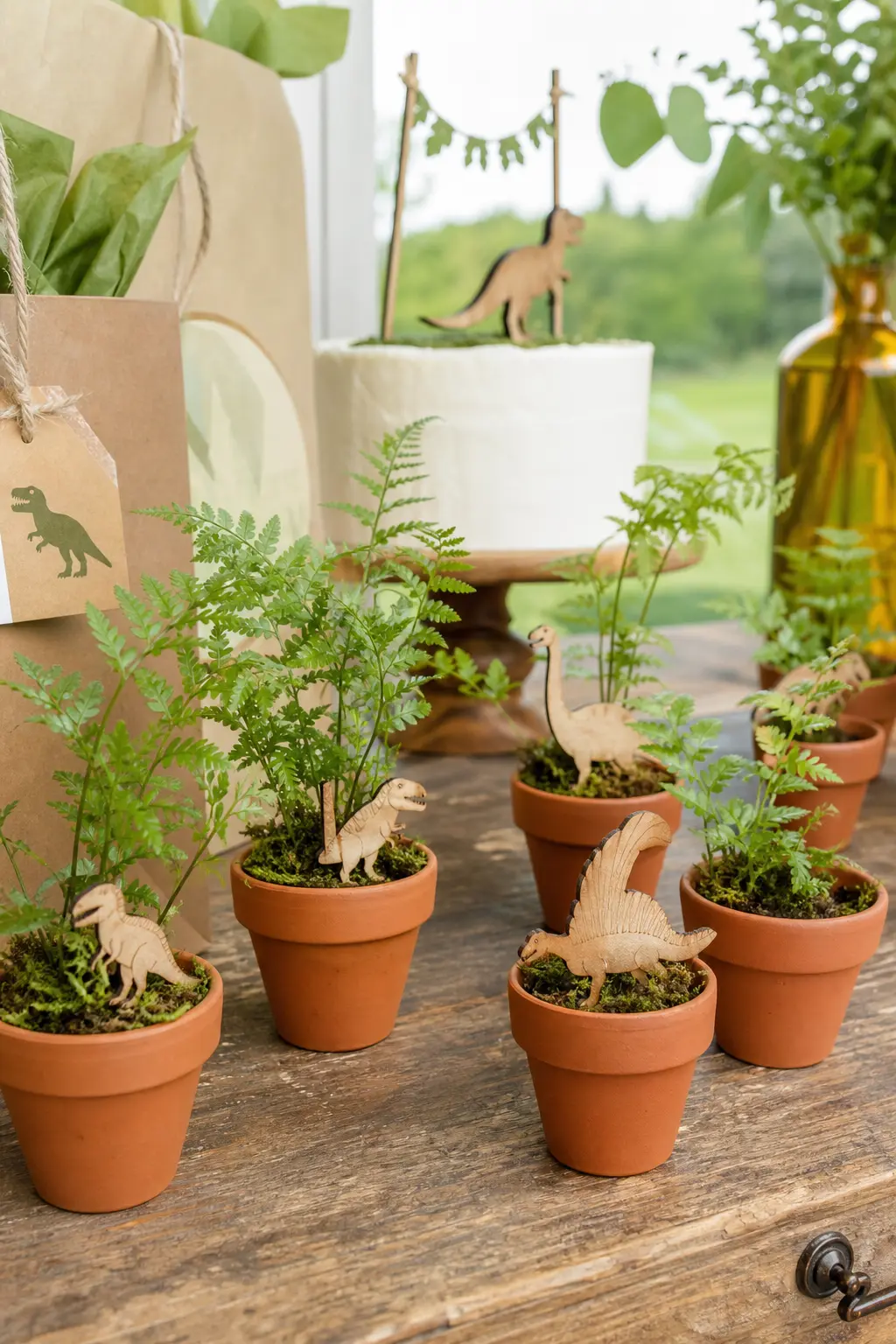 Mini Fern and Figure Favor Pots — Small terracotta pots planted with a single fern sprig, each with one wooden dinosaur figure tucked into the soil, give