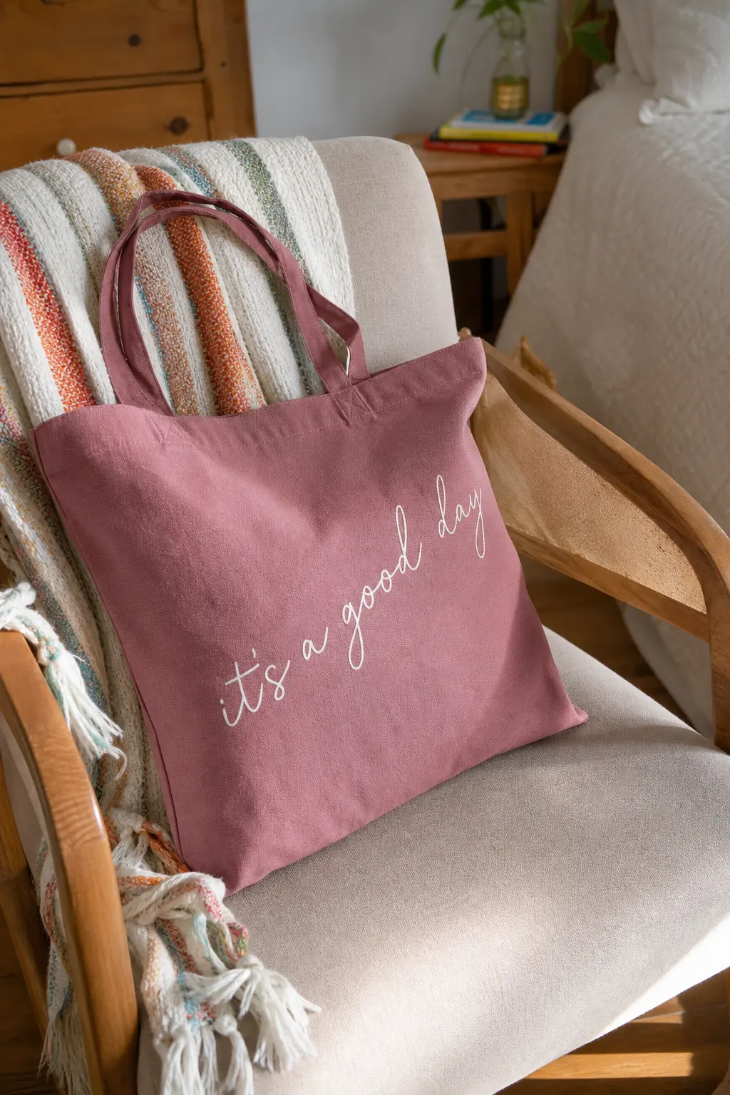 Little Phrase Script Tote — A short phrase in loose cream script runs diagonally across a dusty rose canvas bag, kept to one line and one colour so it reads