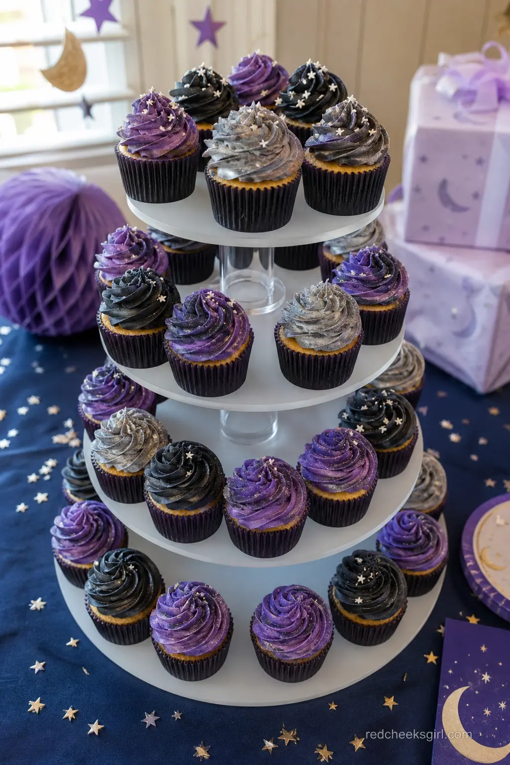 Galaxy Swirl Cupcake Tower — Cupcakes swirled in purple, black and silver frosting like a tiny galaxy stack neatly onto a plain tiered stand. Twinkle little