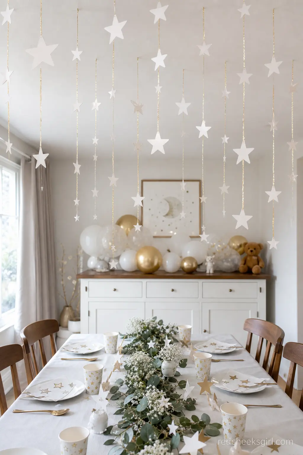 Hanging Paper Star Garland Ceiling — Strings of white paper stars on gold thread hung from the ceiling above the table add height without any bulky decor on