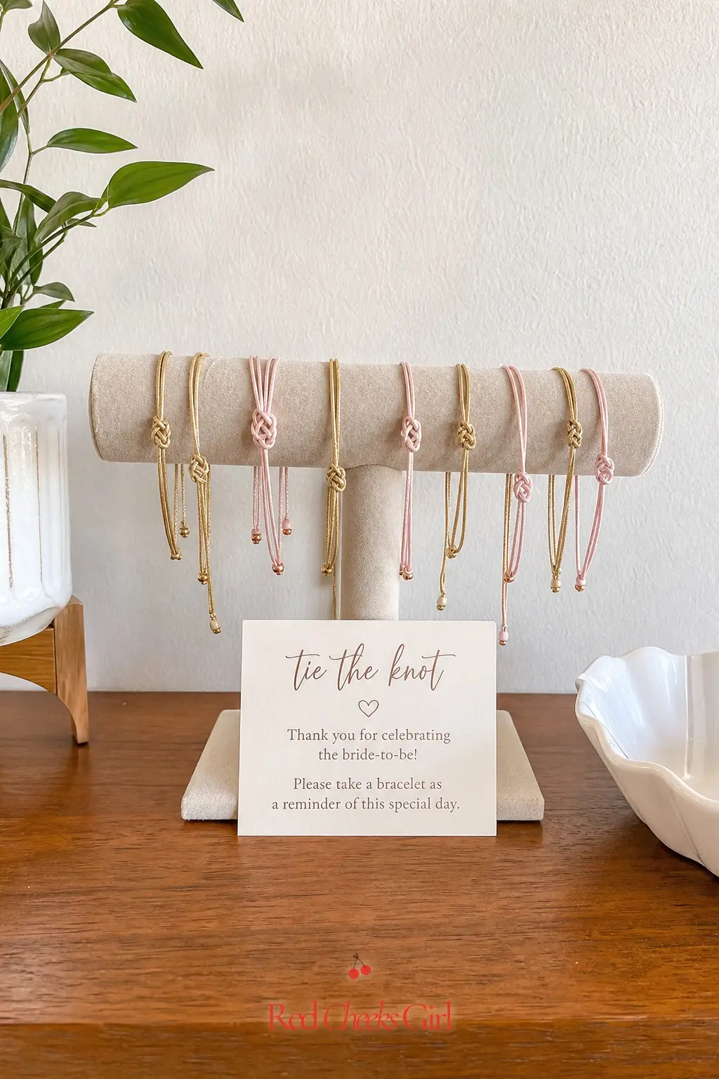 Friendship Knot Bracelet Display — Thin knotted bracelets, laid out on a small velvet stand, double as favor and decor at once, and guests tend to put them on