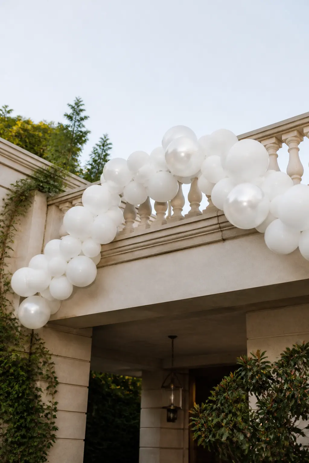 White Garland Along a Balcony Railing with the Ceremony Below — A balcony garland works differently from every other installation because it is seen from below