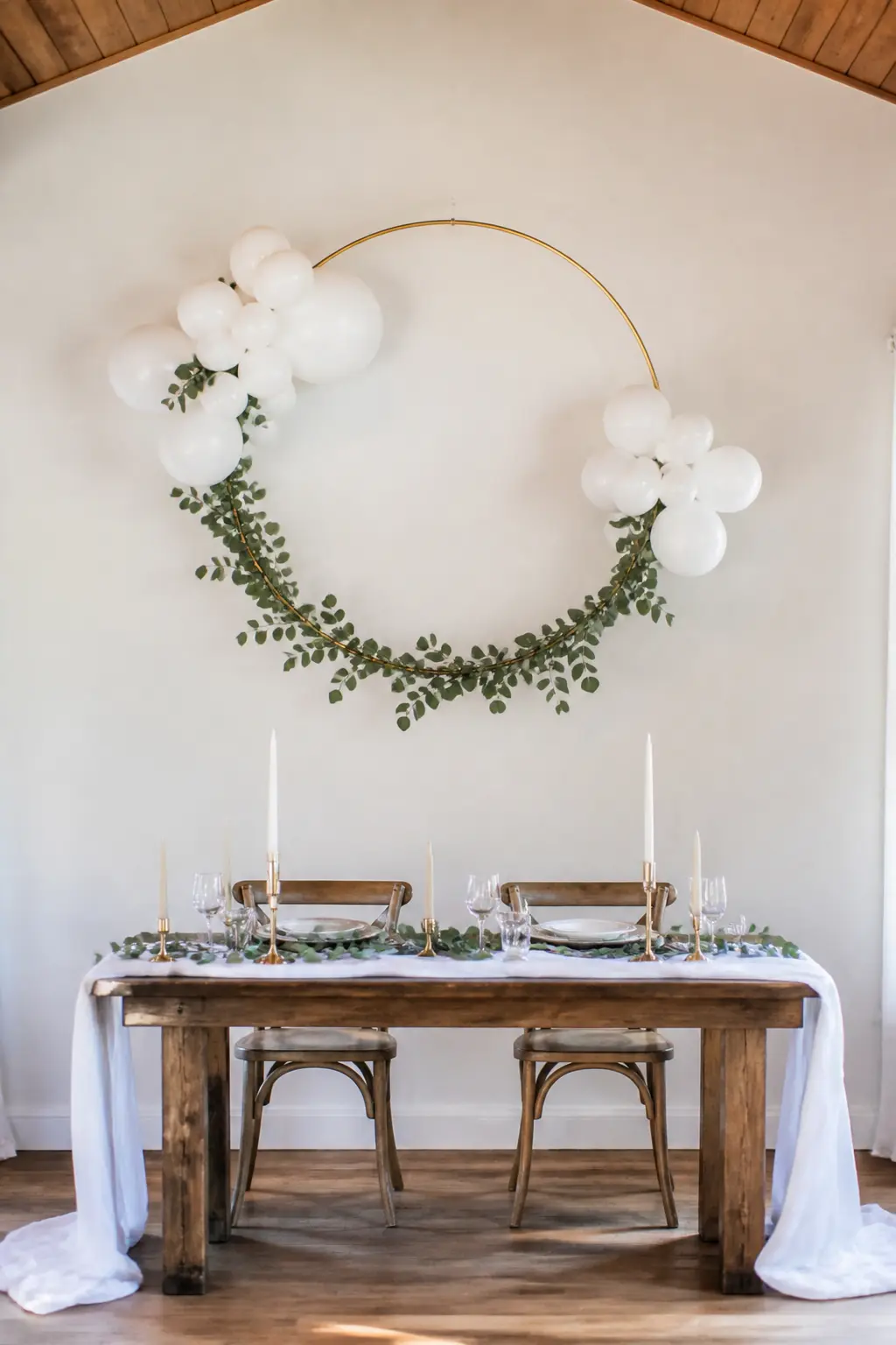 White Hoop Above a Sweetheart Table with Eucalyptus Around the Ring — A single hoop hung above the sweetheart table replaces a full arch with something more