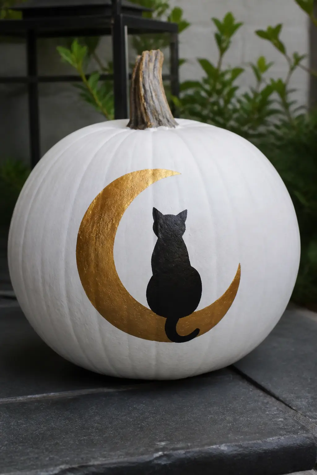 Black Cat on a Gold Crescent Moon — A silhouette of a sitting cat painted in solid black sits on a gold crescent moon painted in the lower half of the pumpkin