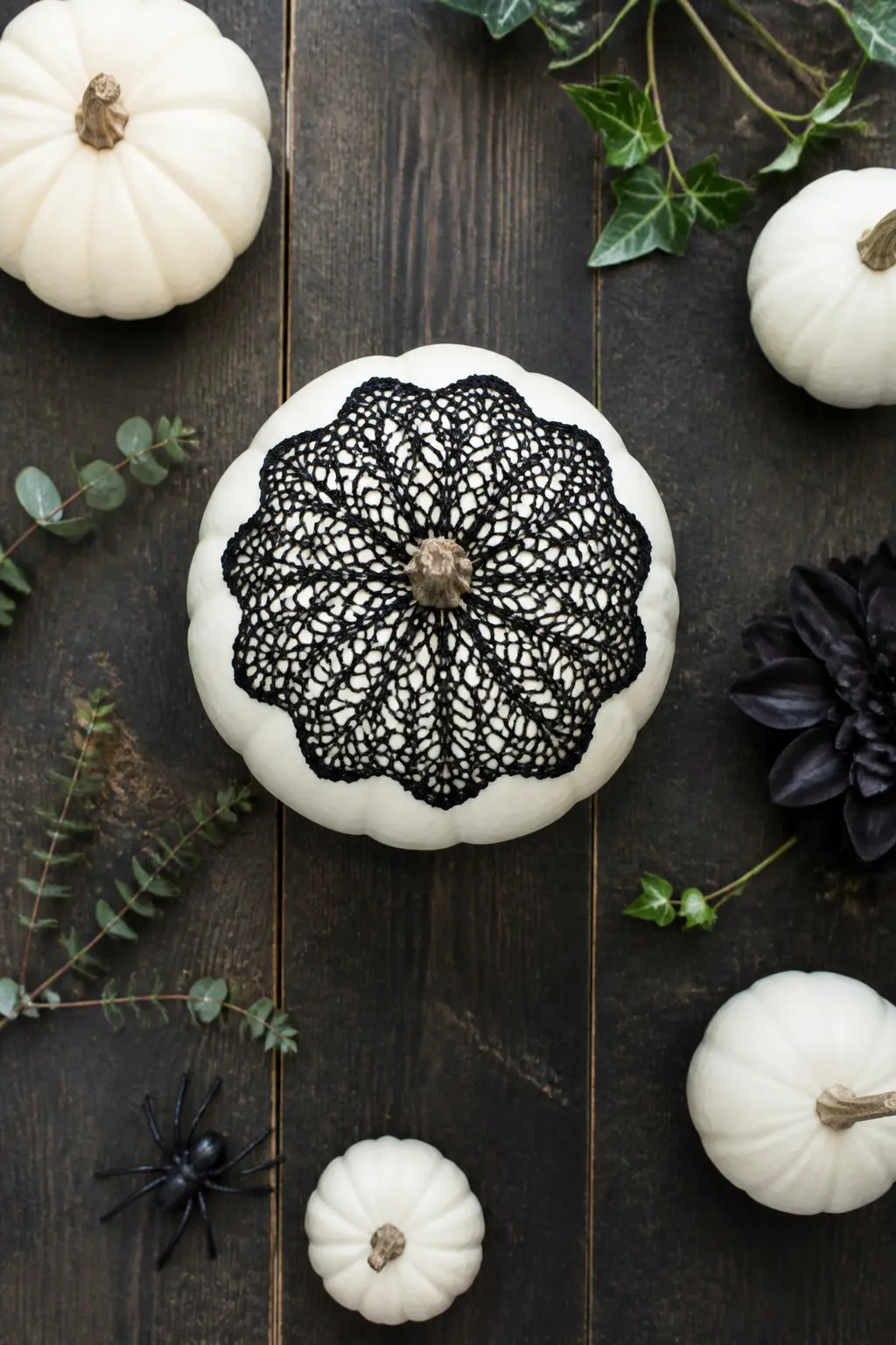 Black Lace Doily Cap — A black paper or fabric lace doily is laid flat on the very top of the pumpkin, centred over the stem, so it drapes slightly over the