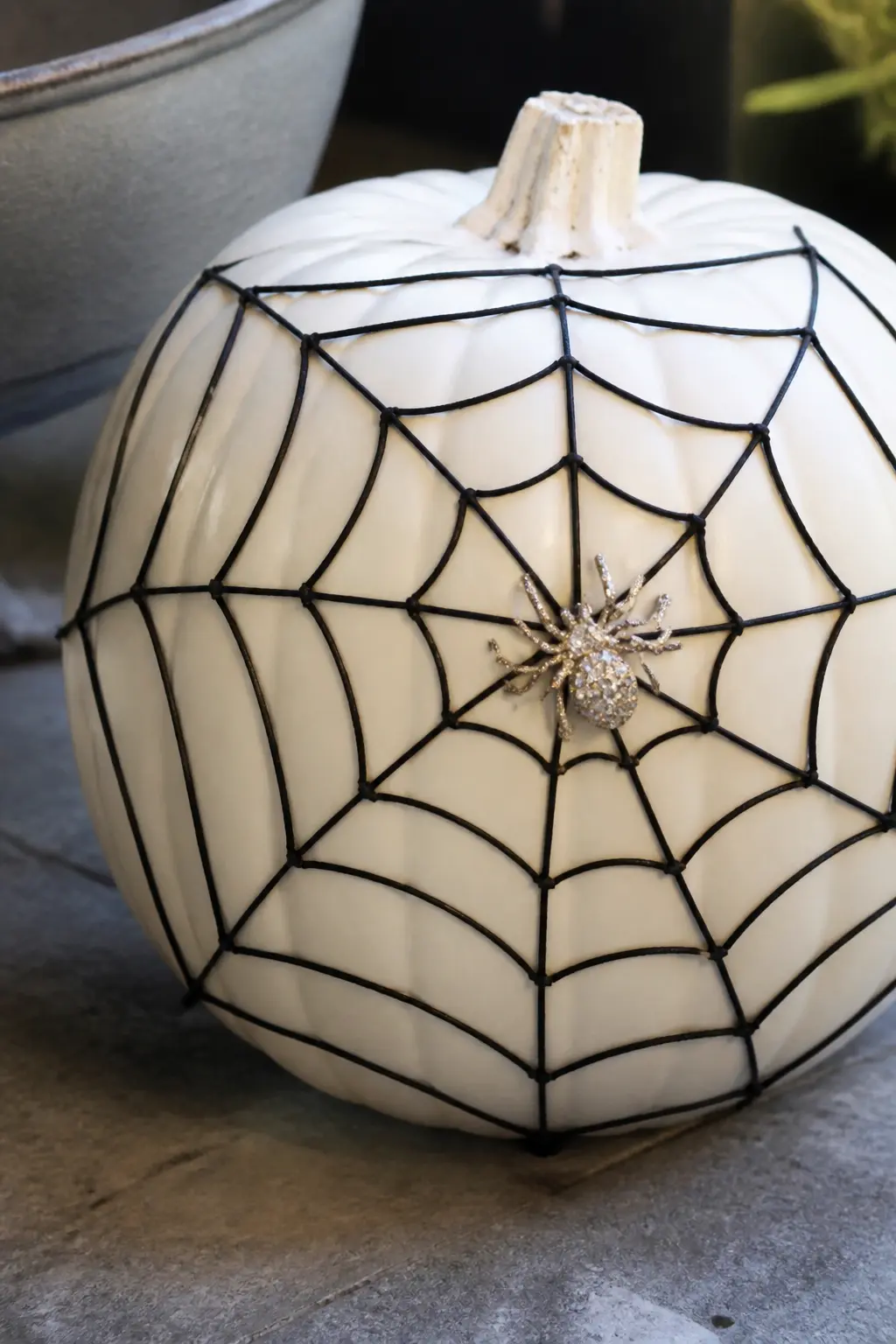 Black Spider Web With Rhinestone Spider — A spider web drawn with a fine black paint pen covers most of one side of the pumpkin, starting from a central point
