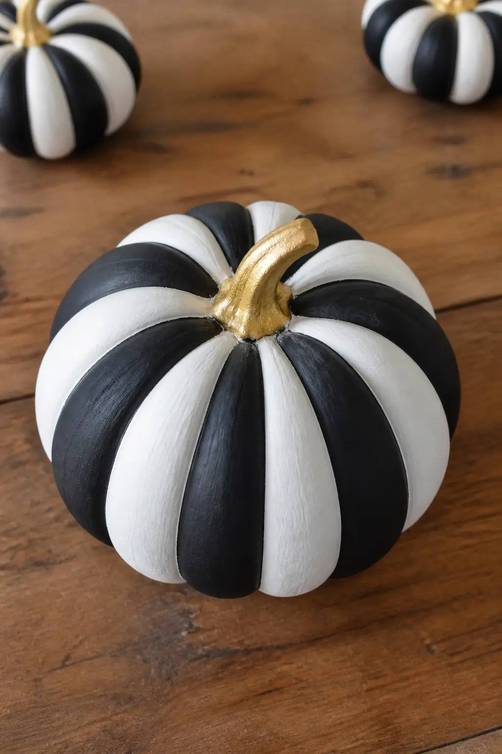 Black Stripes on Ridges With a Gold Stem — Black paint follows every other ridge of the pumpkin from top to bottom, creating natural vertical stripes that