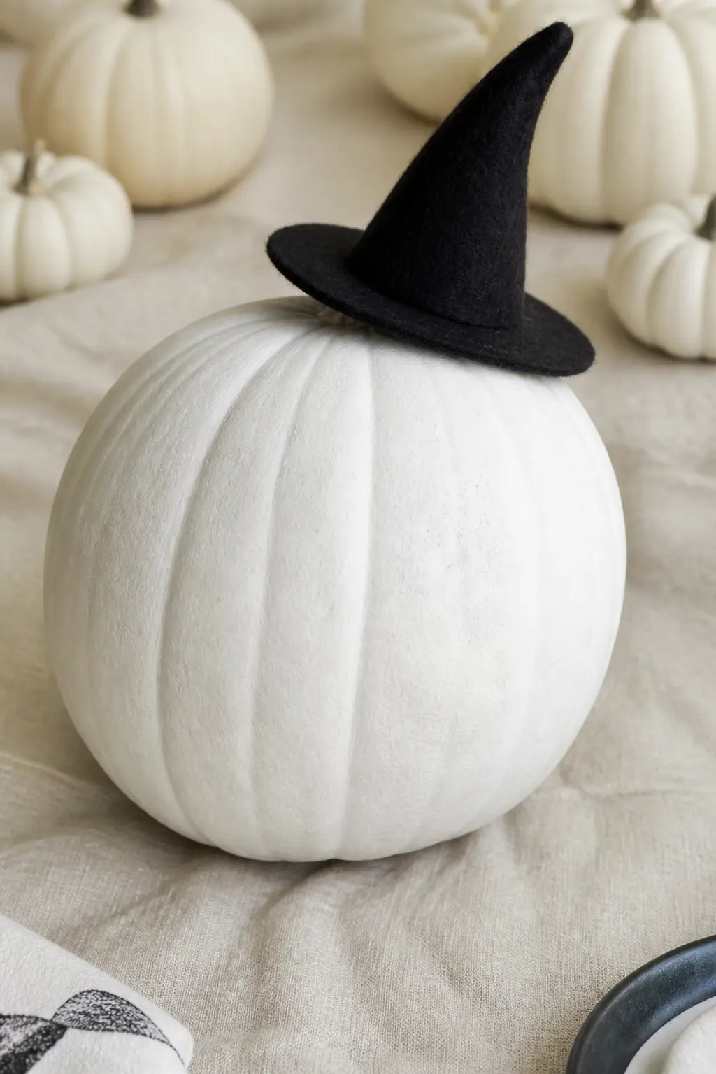 Felt Witch Hat Glued at an Angle — A miniature felt witch hat, tilted at an angle across the top of the pumpkin and fixed with strong glue or a thin wire