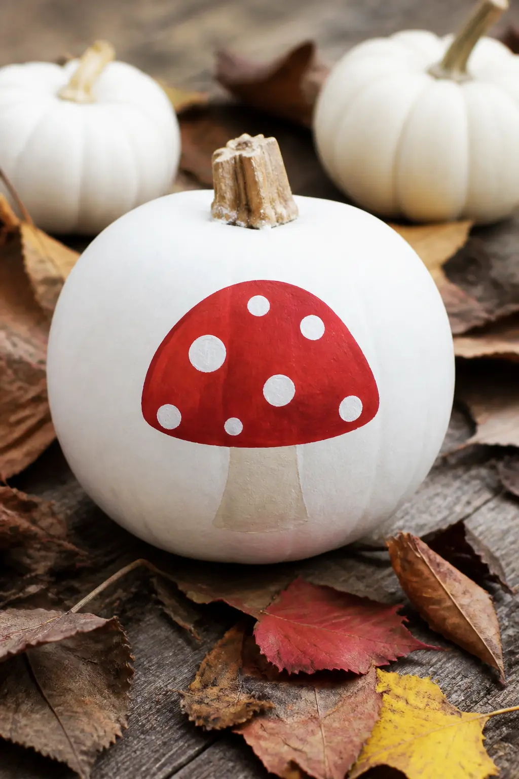 Red Mushroom With White Spots — A classic Amanita-style mushroom painted in red with white spots sits centred on the front of the pumpkin, cap upward. White