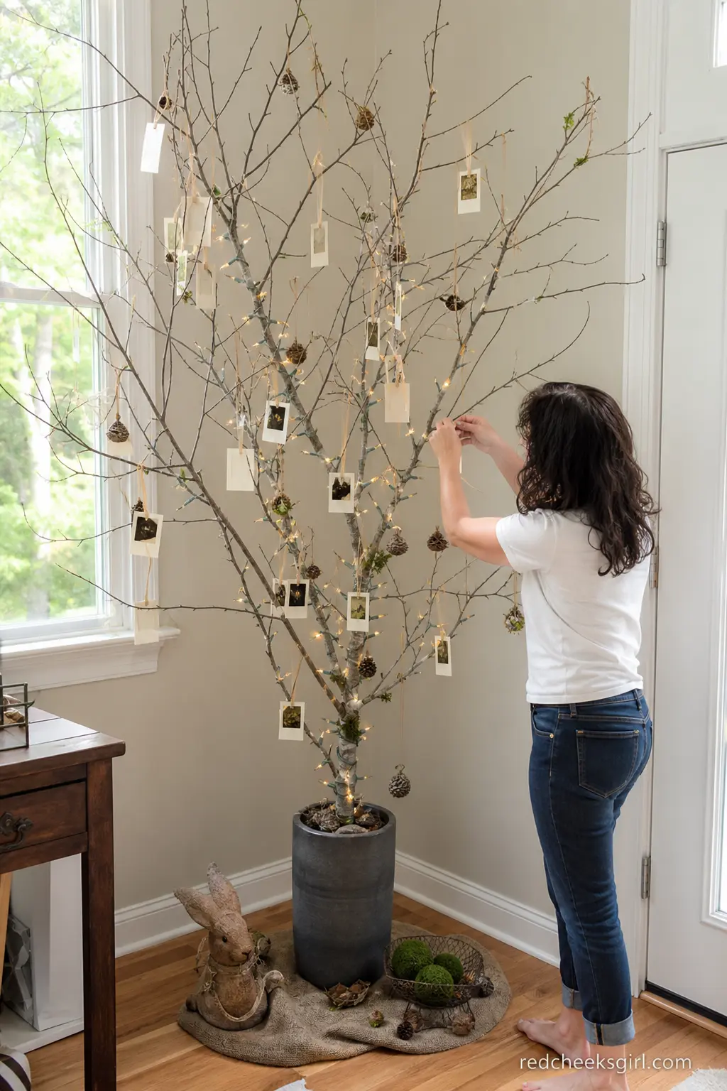 A Branch and Photo Guest Book Tree — A bare branch stood in a weighted vase, hung with small cream polaroid-style frames on twine, invites guests to leave a