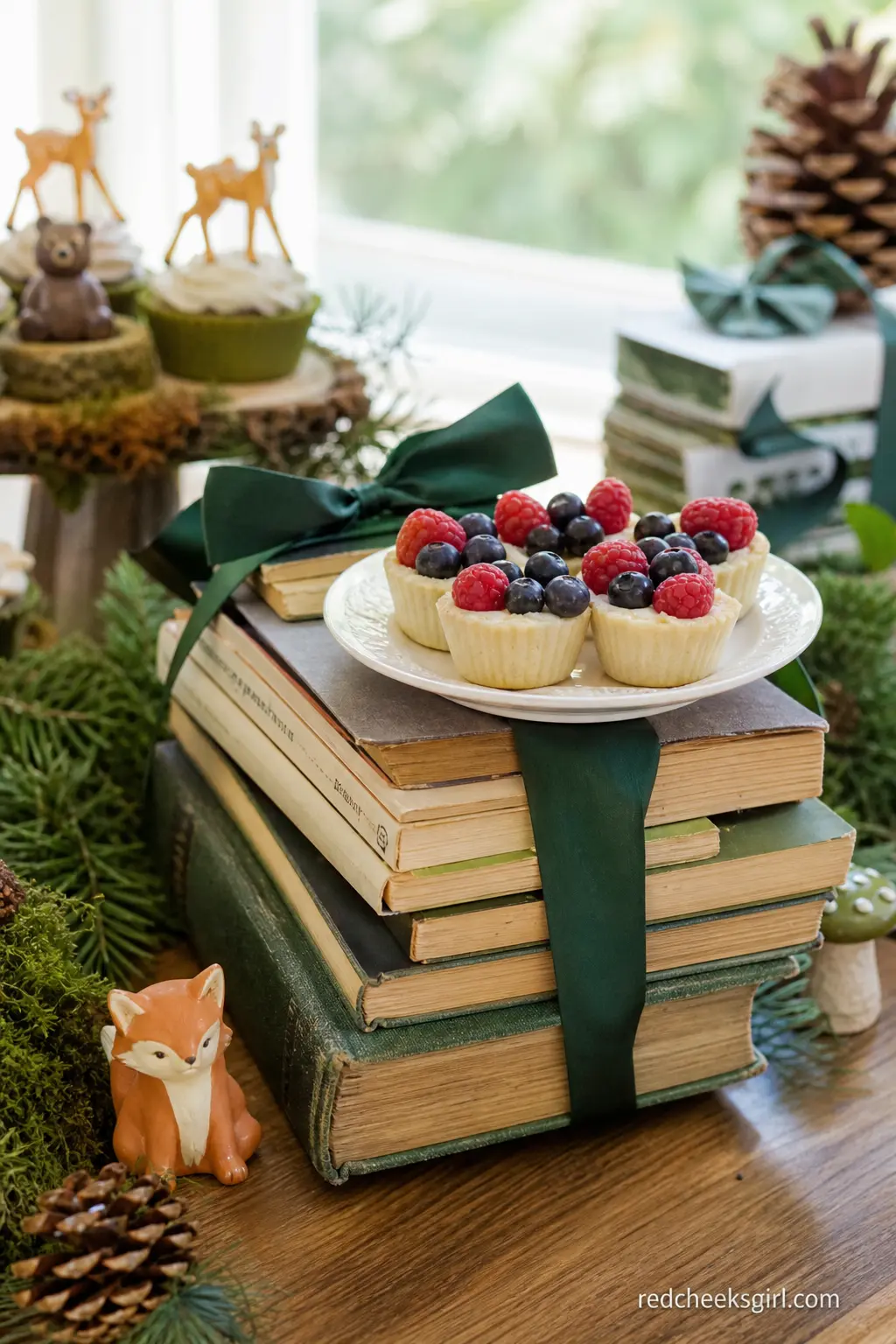 A Vintage Storybook Stack Used as Cake Table Riser — A stack of secondhand storybooks with cream, aged pages, tied with forest green ribbon, raises a small