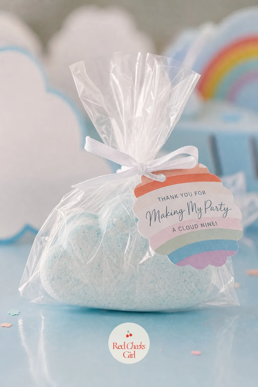 A Cloud-Shaped Bath Bomb Favor — A molded bath bomb shaped like a puffy cloud in pale sky blue or white, with a hidden rainbow colored core that swirls out